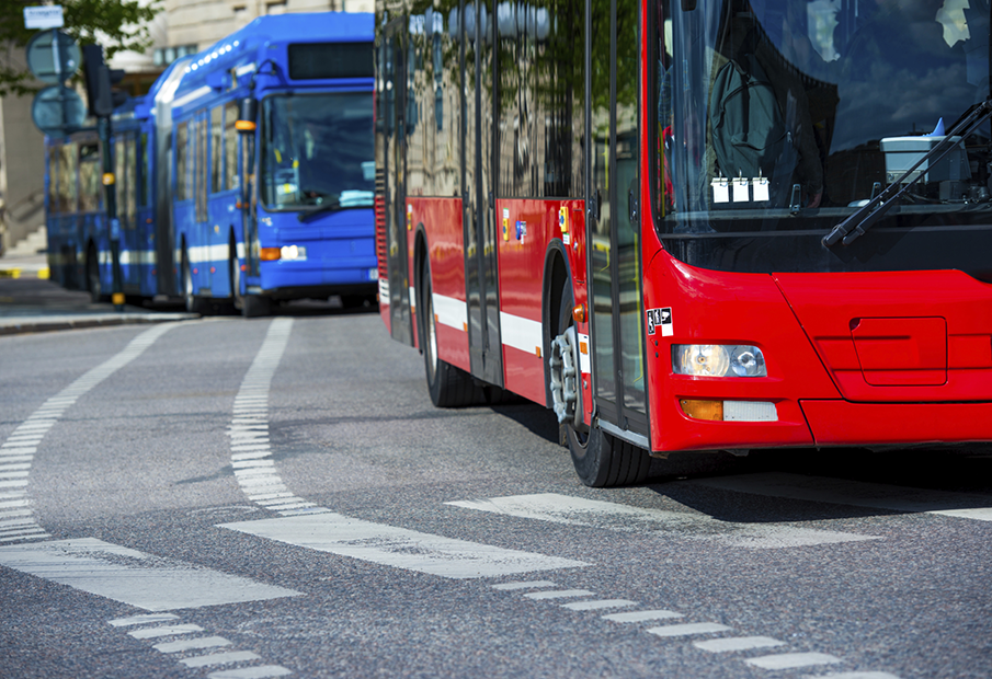 A blue bus behind a red bus