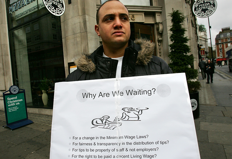 Man holding up a sign about minimum wage