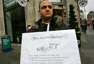 Man holding up a sign about minimum wage
