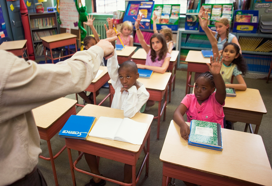 Multicultural kids raising their hands in a classroom