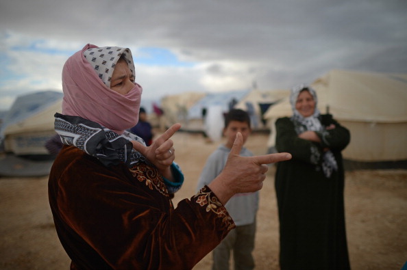 MAFRAQ, JORDAN - JANUARY 29: A woman gestures as Syrian refugees go about their daily business in the Za?atari refugee camp on January 29, 2013 in Mafraq, Jordan. Record numbers of refugees are fleeing the violence and bombings in Syria to cross the borders to safety in northern Jordan and overwhelming the Za'atari camp. The Jordanian government are appealing for help with the influx of refugees as they struggle to cope with the sheer numbers arriving in the country. (Photo by Jeff Mitchell/Getty Images)