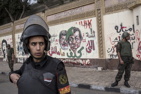 CAIRO, EGYPT - DECEMBER 14:  Soldiers stand guard in front of the presidential palace as anti-scaf graffiti is seen on the wall on December 14, 2012 in Cairo, Egypt. Opponents and supporters of Egyptian President Mohamed Morsi staged final rallies in Cairo ahead of tomorrow's referendum vote on the country's draft constitution that was rushed through parliament in an overnight session on November 29. The country's new draft constitution, passed by a constitutional assembly dominated by Islamists, will go to a referendum vote on December 15.  (Photo by Daniel Berehulak/Getty Images)