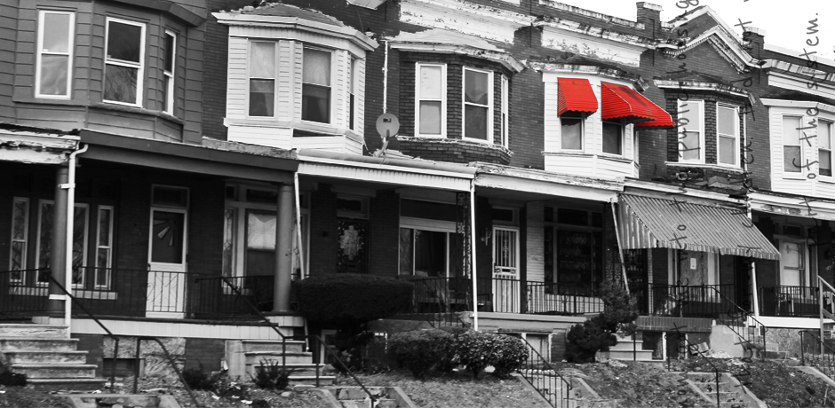 A strip of homes in black and white. One window has red shades.