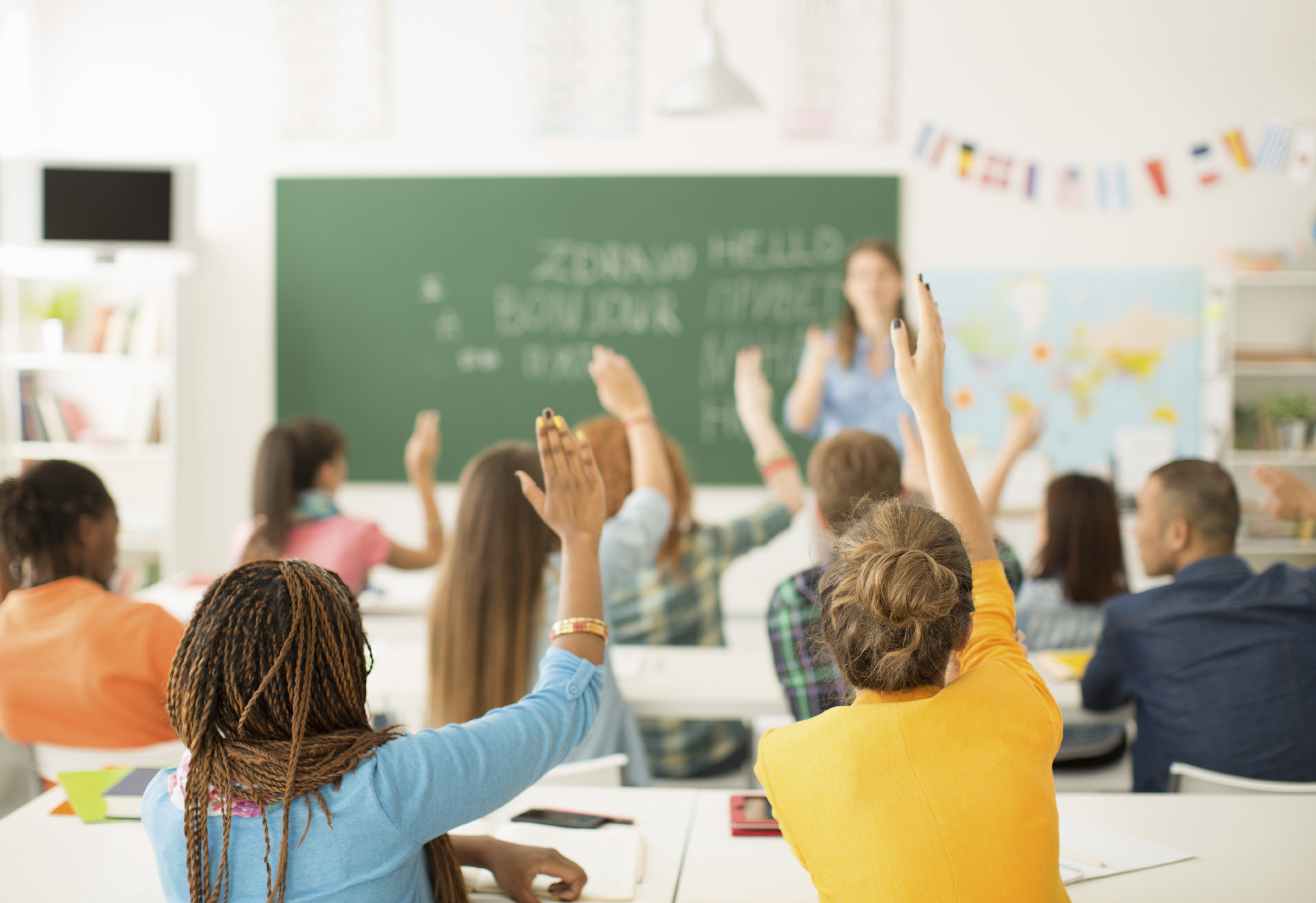 Two women in a multicultural classroom raising their hands