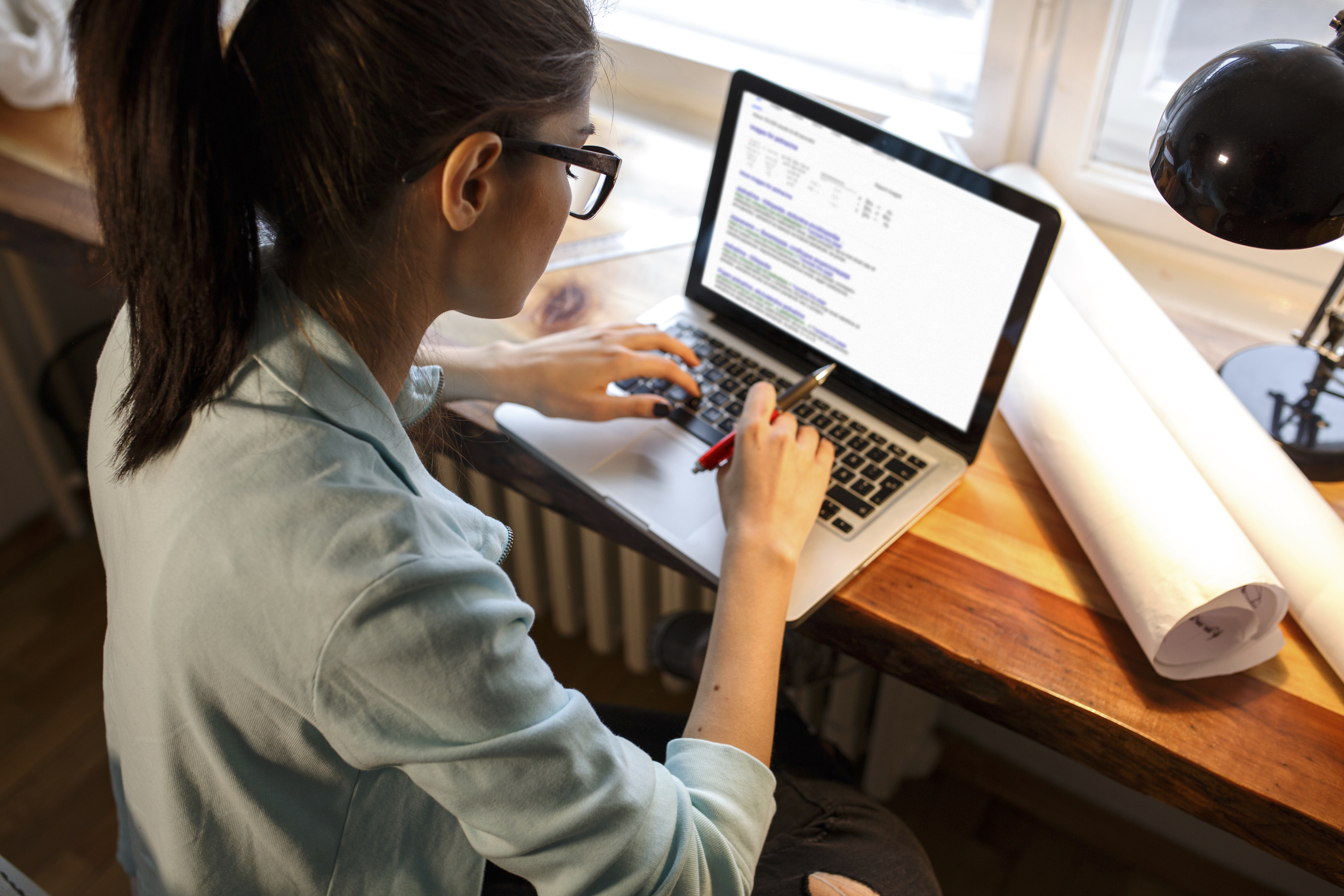 Young female blogger working at home.She sitting in her working room and typing something on laptop.