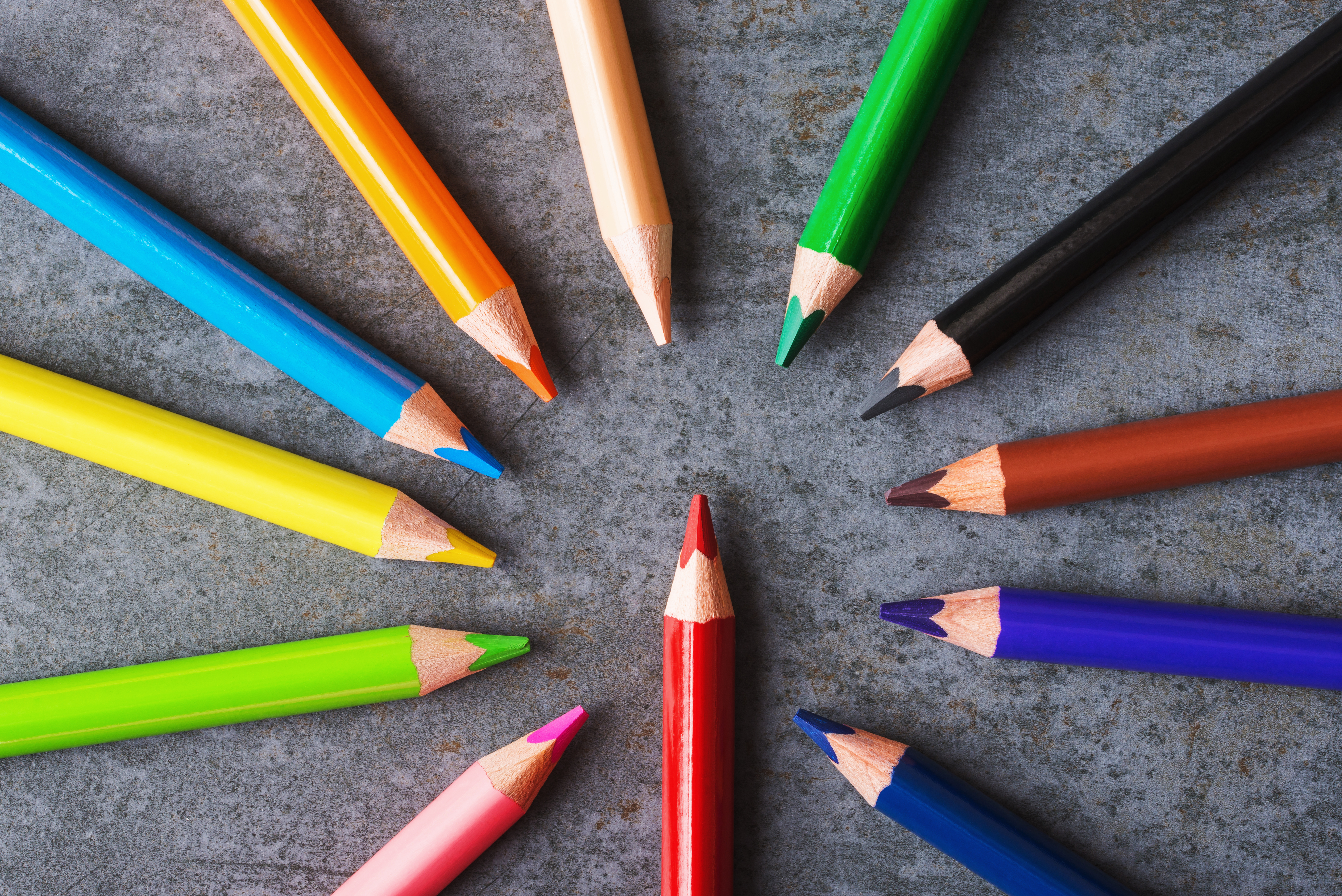 Multicolored pencils on grey background.