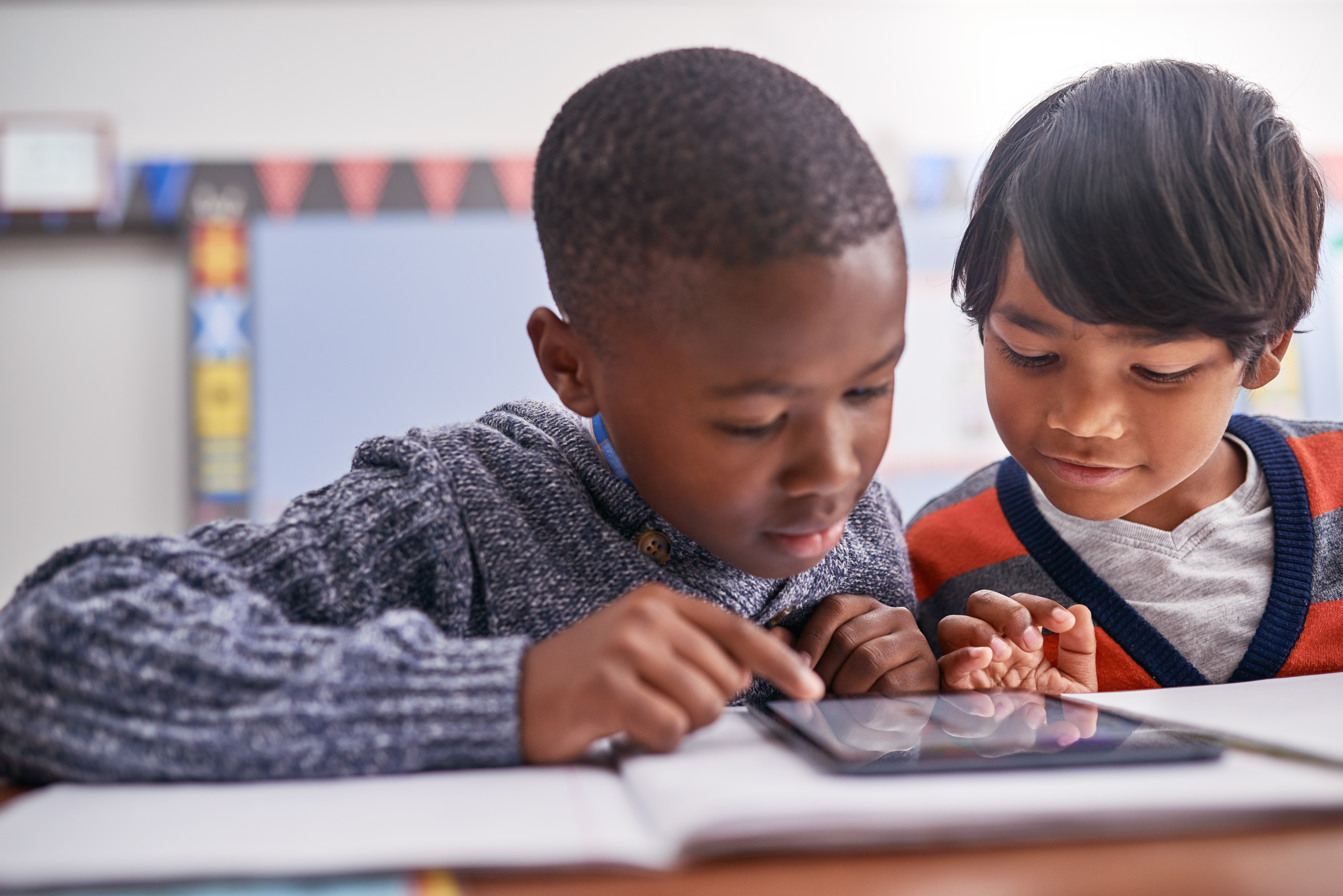 Cropped shot of elementary school children using a tablet in class
