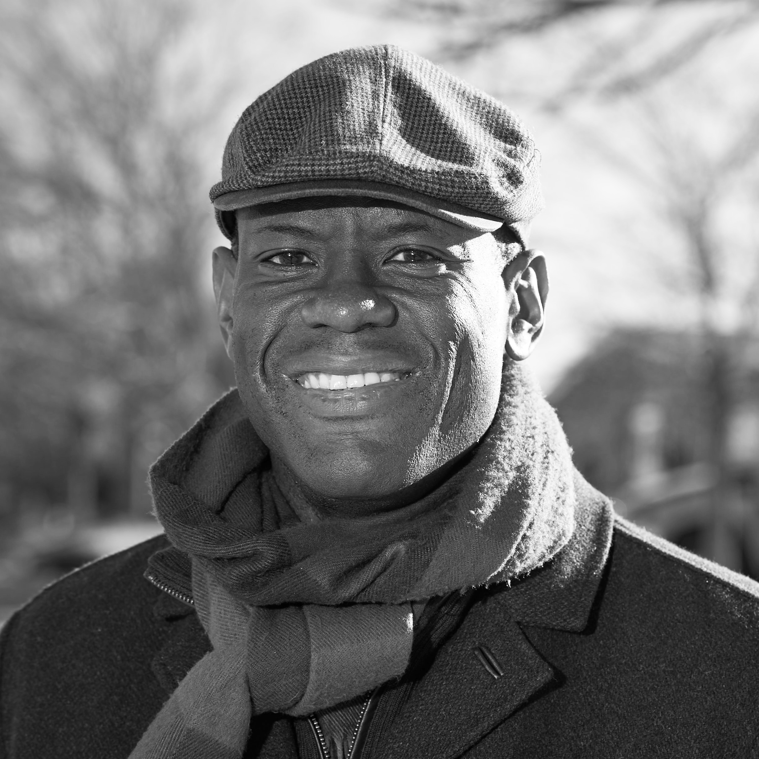 a black and white photo of a man wearing a hat and scarf