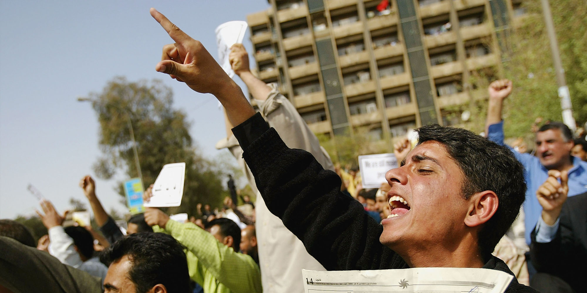 a crowd of people holding up signs and pointing at something