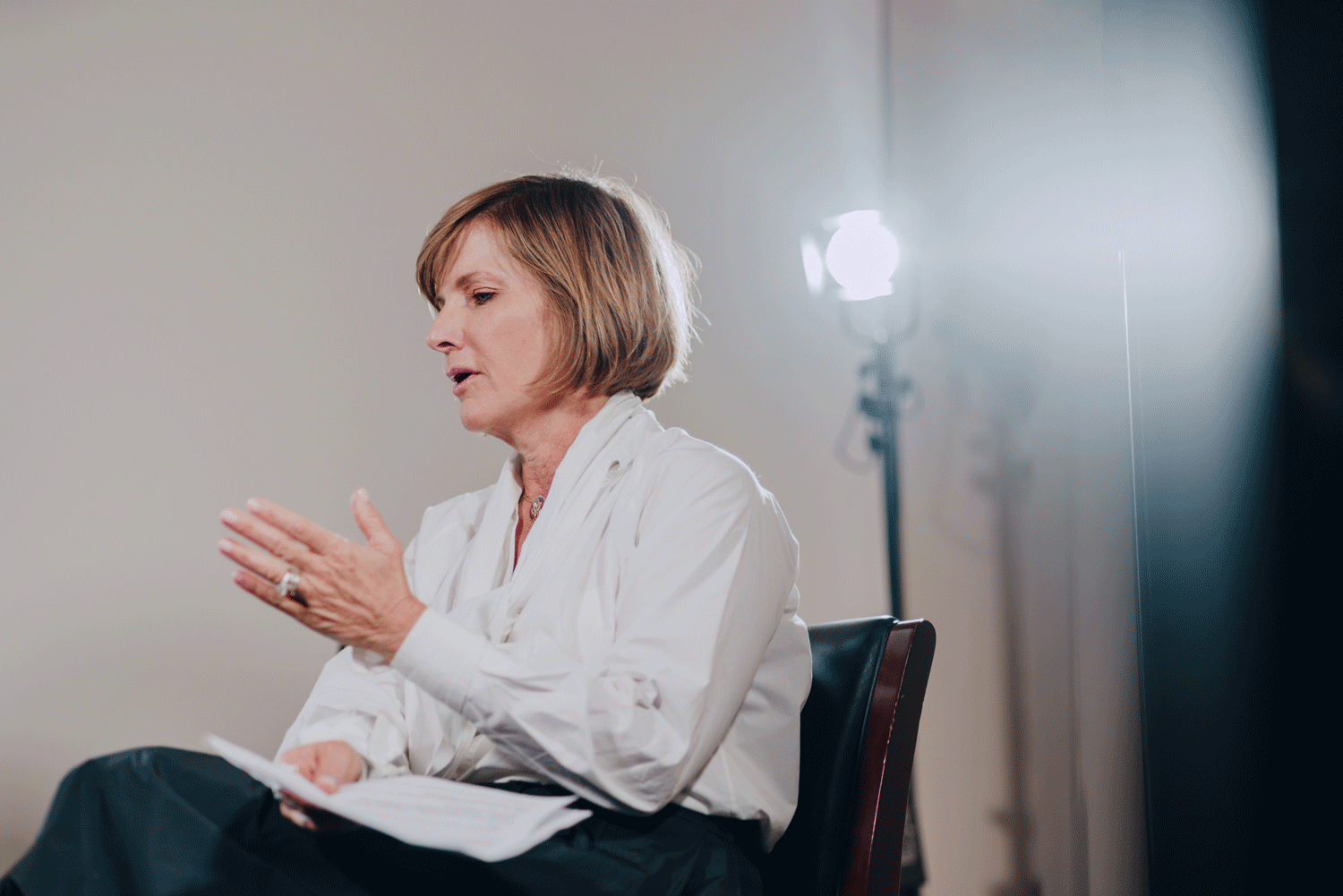 a woman sitting in a chair with her hands folded