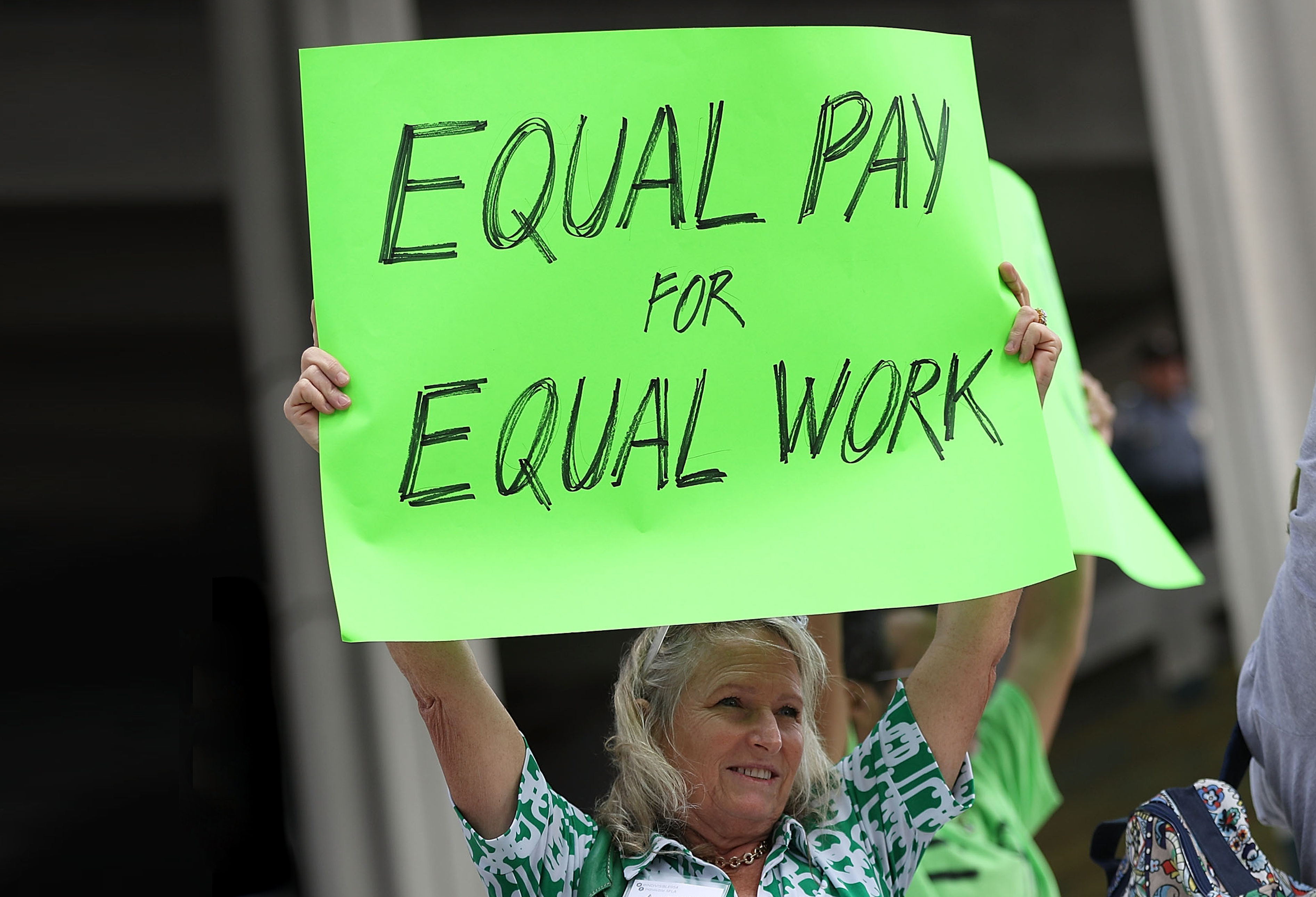 a woman holding a sign that says equal pay for equal work