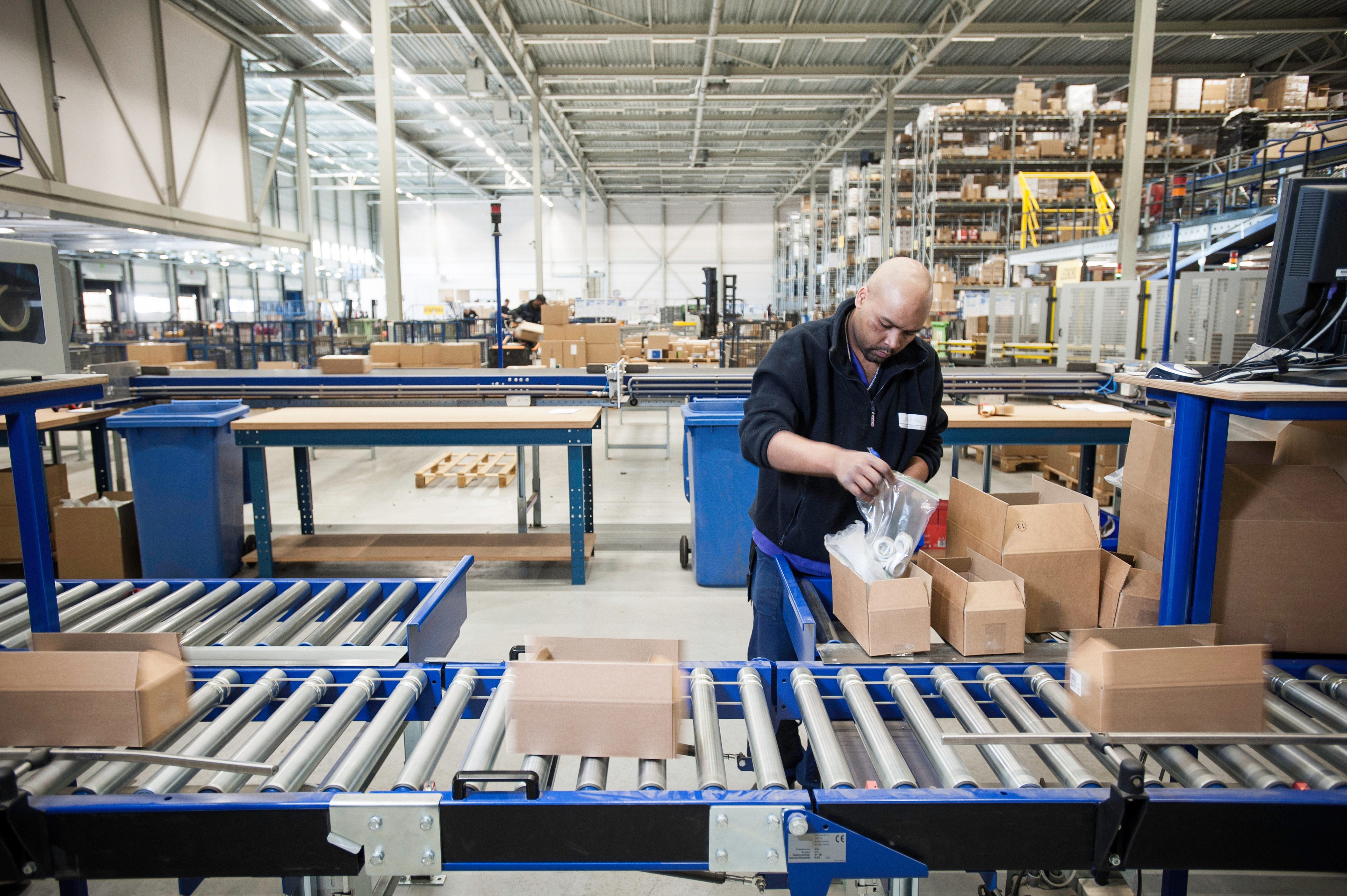 Male warehouse worker packing cardboard boxes for conveyer belt