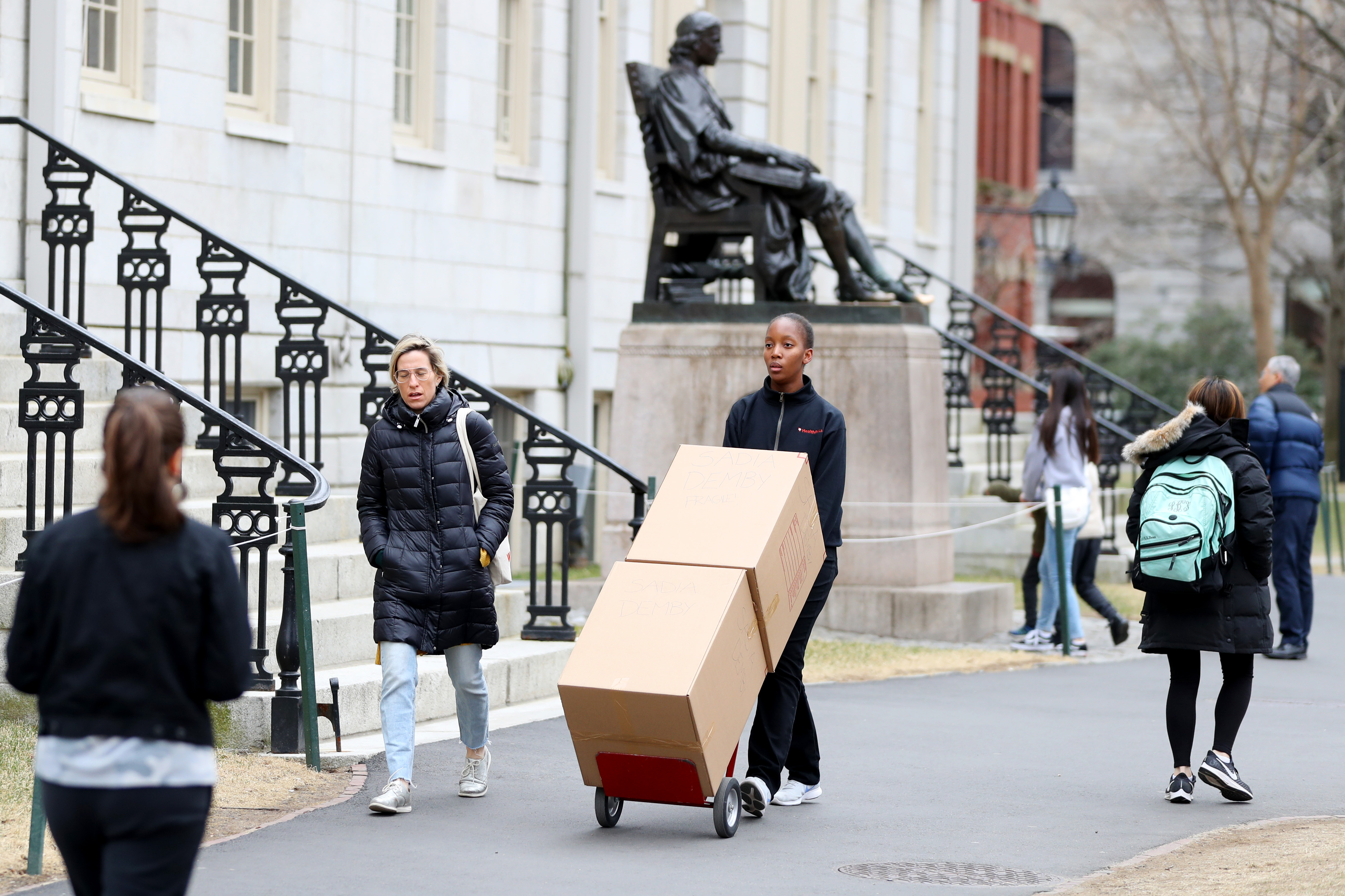CAMBRIDGE, MASSACHUSETTS - MARCH 12: Sophomore Sadia Demby moves her belongings through Harvard Yard on the campus of Harvard University on March 12, 2020 in Cambridge, Massachusetts. Students have been asked to move out of their dorms by March 15 due to the Coronavirus (COVID-19) risk. All classes will be moved online for the rest of the spring semester.  (Photo by Maddie Meyer/Getty Images)