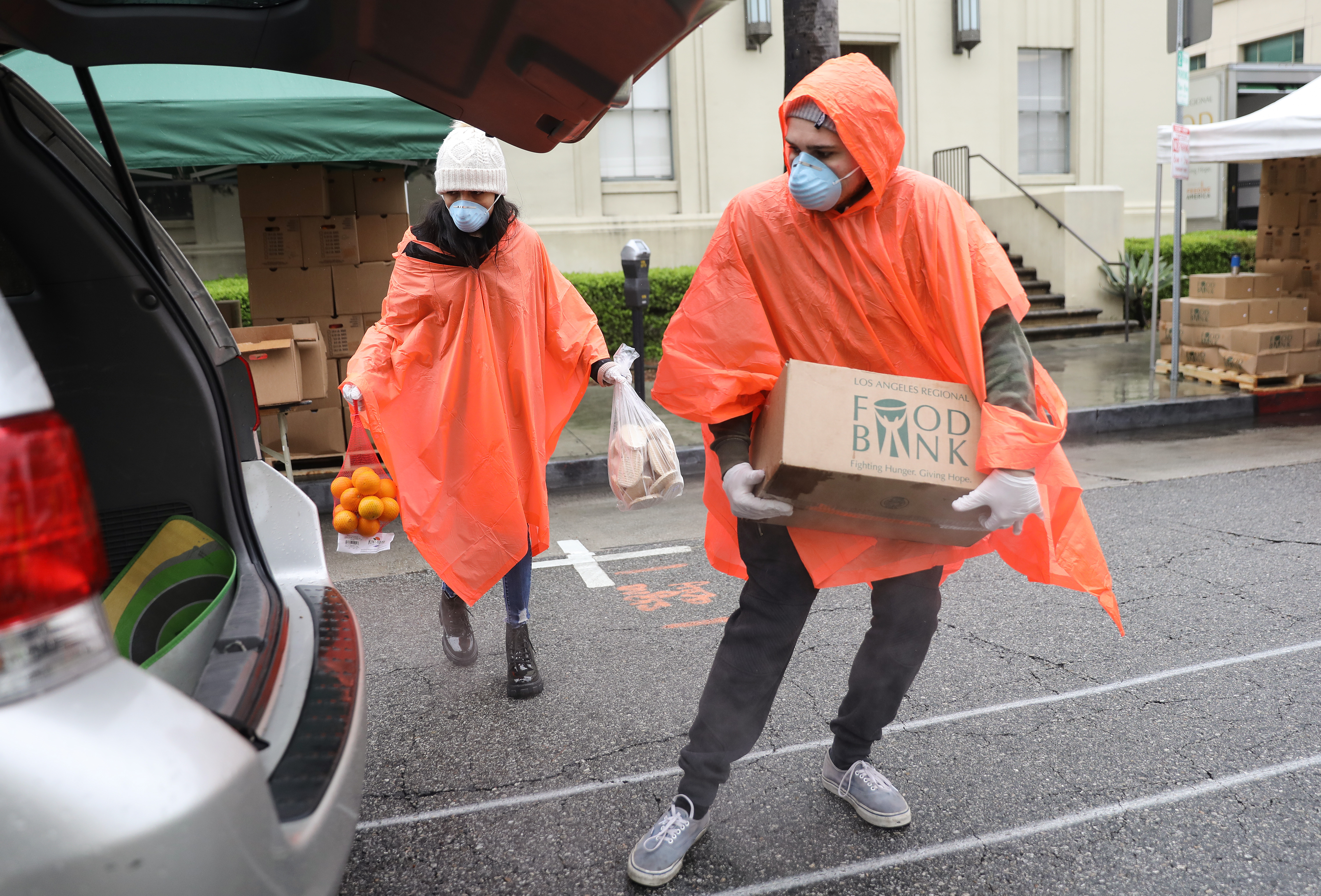 VAN NUYS, CALIFORNIA - APRIL 09: Volunteers load food into a recipient's trunk at a Food Bank distribution for those in need as the coronavirus pandemic continues on April 9, 2020 in Van Nuys, California. Organizers said they had distributed food for 1,500 families amid the spread of COVID-19.  (Photo by Mario Tama/Getty Images)