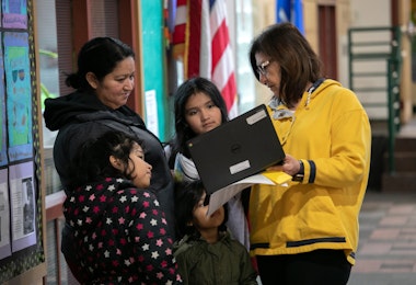 STAMFORD, - MARCH 17: Bilingual teacher Maria Sanislo (R) explains a Google Chromebook to a family at KT Murphy Elementary School on March 17, 2020 in Stamford, Connecticut. Stamford Public Schools closed last week to help slow the spread of COVID-19, and students are now