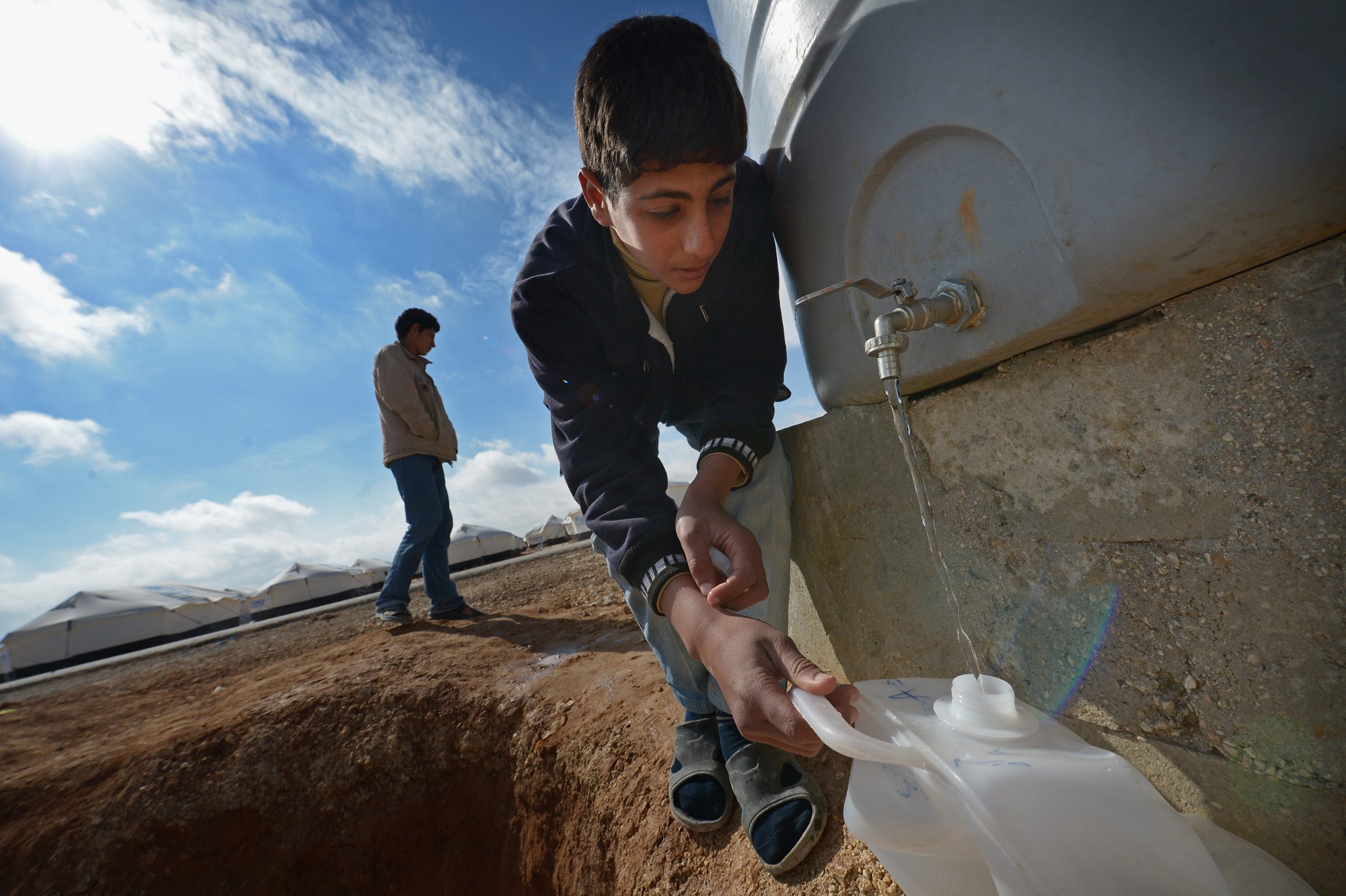 MAFRAQ, JORDAN - JANUARY 29:  Syrian refugees gather water as they go about their daily business in the Za’atari refugee camp on January 29, 2013 in Mafraq, Jordan. Record numbers of refugees are fleeing the violence and bombings in Syria to cross the borders to safety in northern Jordan and overwhelming the Za'atari camp. The Jordanian government are appealing for help with the influx of refugees as they struggle to cope with the sheer numbers arriving in the country.  (Photo by Jeff J Mitchell/Getty Images)