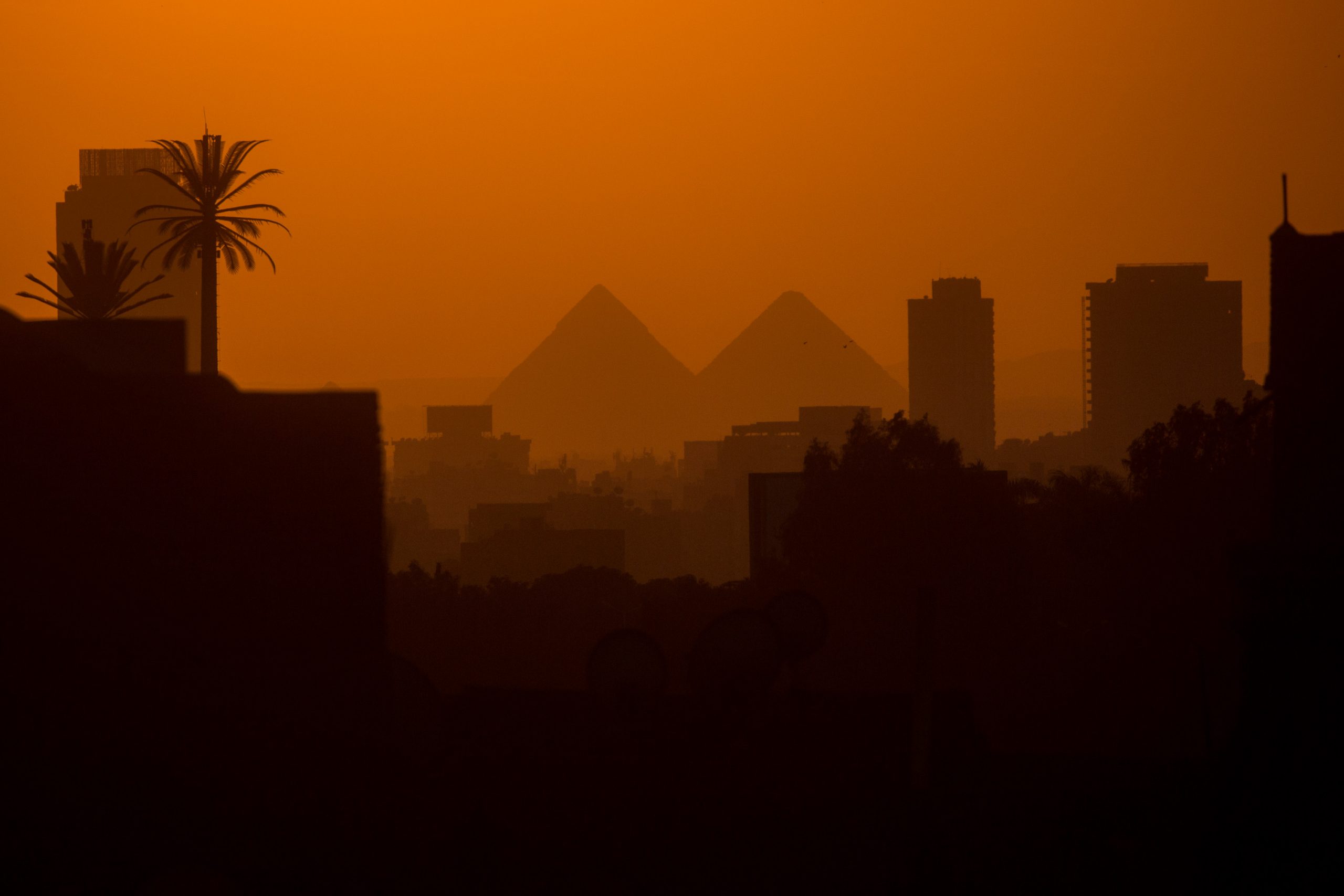 CAIRO, EGYPT - DECEMBER 15: City buildings are seen in front of the famous Giza Pyramids on December 15, 2016 in Cairo, Egypt. Since the 2011 Arab Spring, Egyptians have been facing a crisis, the uprising brought numerous political changes, but also economic turmoil, increased terror attacks and the unravelling of the once strong tourism sector. In recent weeks Egypt has again been hit by multiple bomb blasts, the most recent killed 26 Christians inside the St Peter and St Paul Church during Sunday mass. As Christians took to the streets chanting anti-government slogans, fears grow of an escalation in militant activity which would further deal damage to a country trying to rebuild. In recent months protests against rising fuel and food prices, calls for mass anti-government demonstrations and the continued terror attacks have seen Egyptian president Abdel Fattah Al-Sisi, suffer a significant drop in popularity. Mr. Al-Sisi has promised change, fearing anger and desperation could lead to popular unrest, however inflation currently sits at the highest level in seven years, jobless rates are above 13percent and more than 90million people are said to be living in poverty. The outlook forced the government to seek a $12 billion bailout from the International Monetary Fund, pushing the country to float the Egyptian pound to qualify for the loan. The move led to a sharp devaluation of the Egyptian pound which now sits at 18EGP to the dollar. The turmoil is affecting not only the poor but both the middle-class and the wealthy as food and commodity prices skyrocket.  (Photo by Chris McGrath/Getty Images)