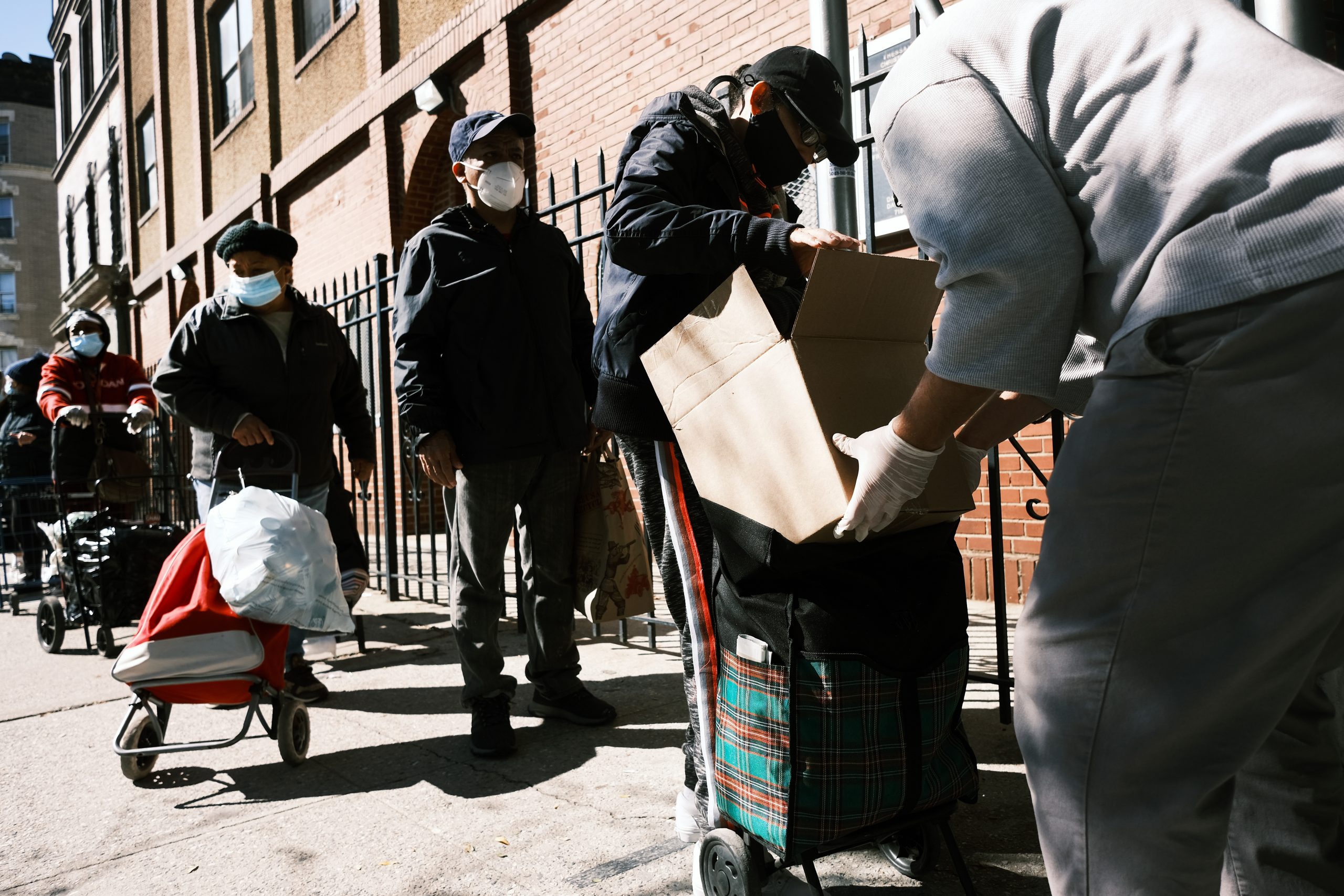 NEW YORK, NEW YORK - OCTOBER 17: People receive food at the Thessalonica Christian Church during a distribution on October 17, 2020 in New York City. The Bronx, a borough which has long struggled with poverty and neglect, has been especially impacted by the COVID-19 pandemic. The official unemployment rate in the Bronx is 21% while the unofficial number is presumed to be almost twice that. With many residents unable to afford health care and being home to a significant amount of front-line workers, the Bronx has the highest COVID-19 death rate in New York City.  (Photo by Spencer Platt/Getty Images)