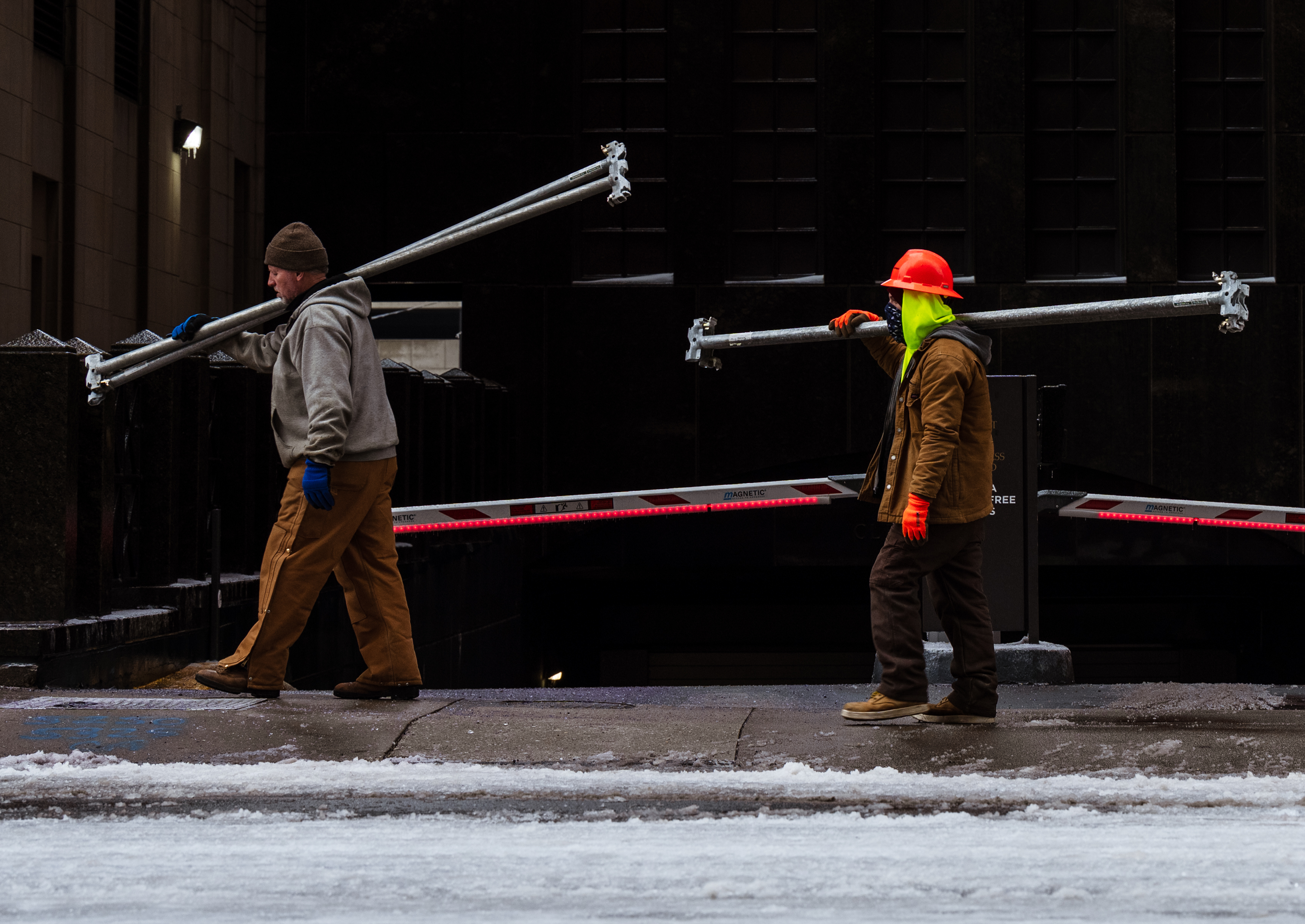 Photograph of construction workers carrying scaffolding beams