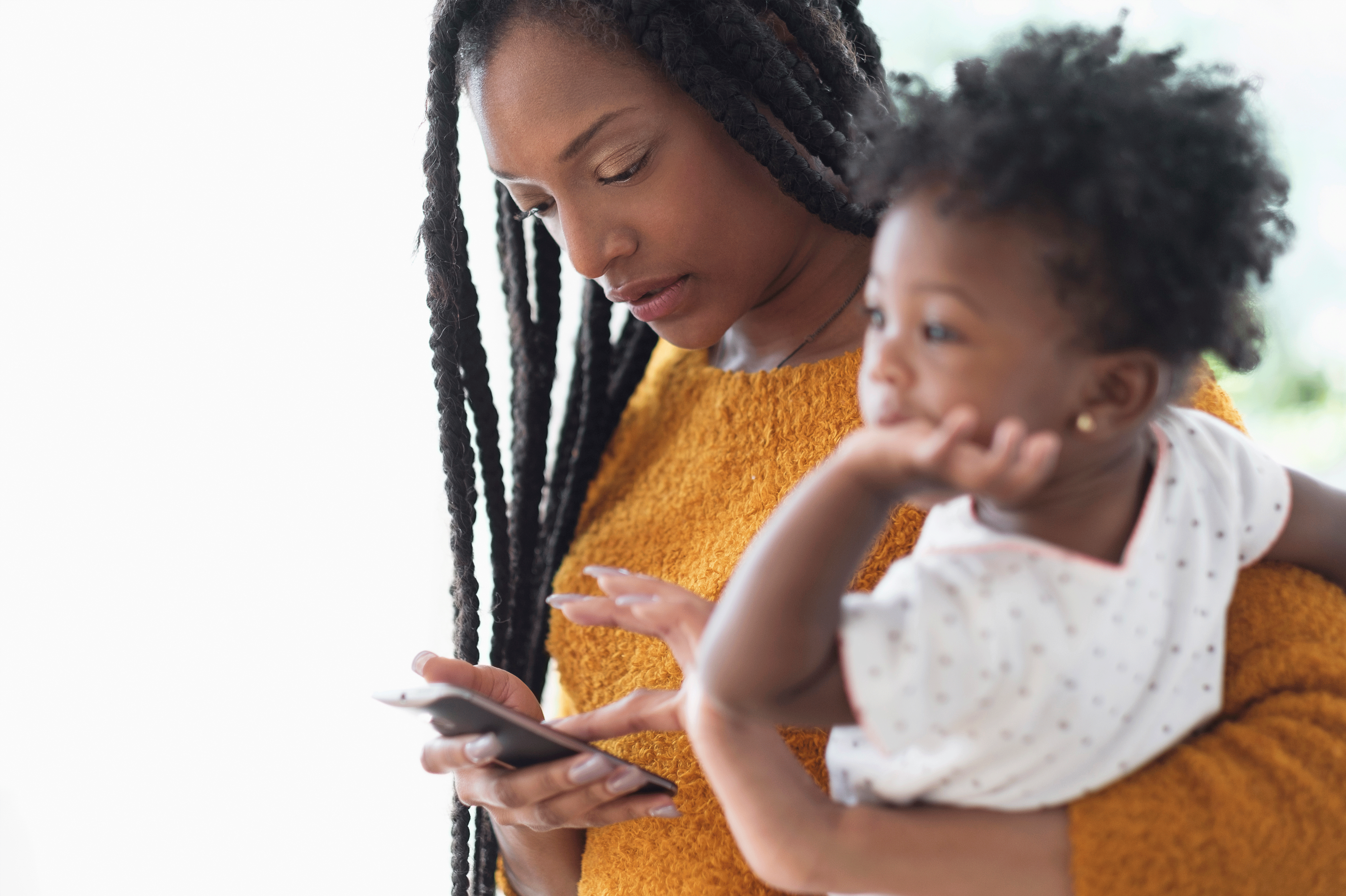 a woman holding a child while looking at a cell phone