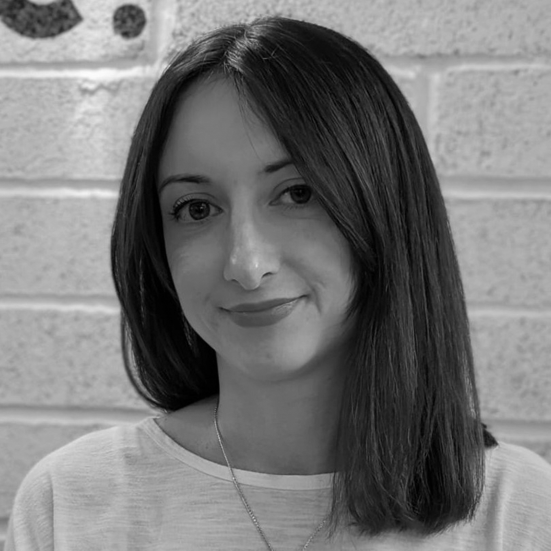 a woman standing in front of a brick wall