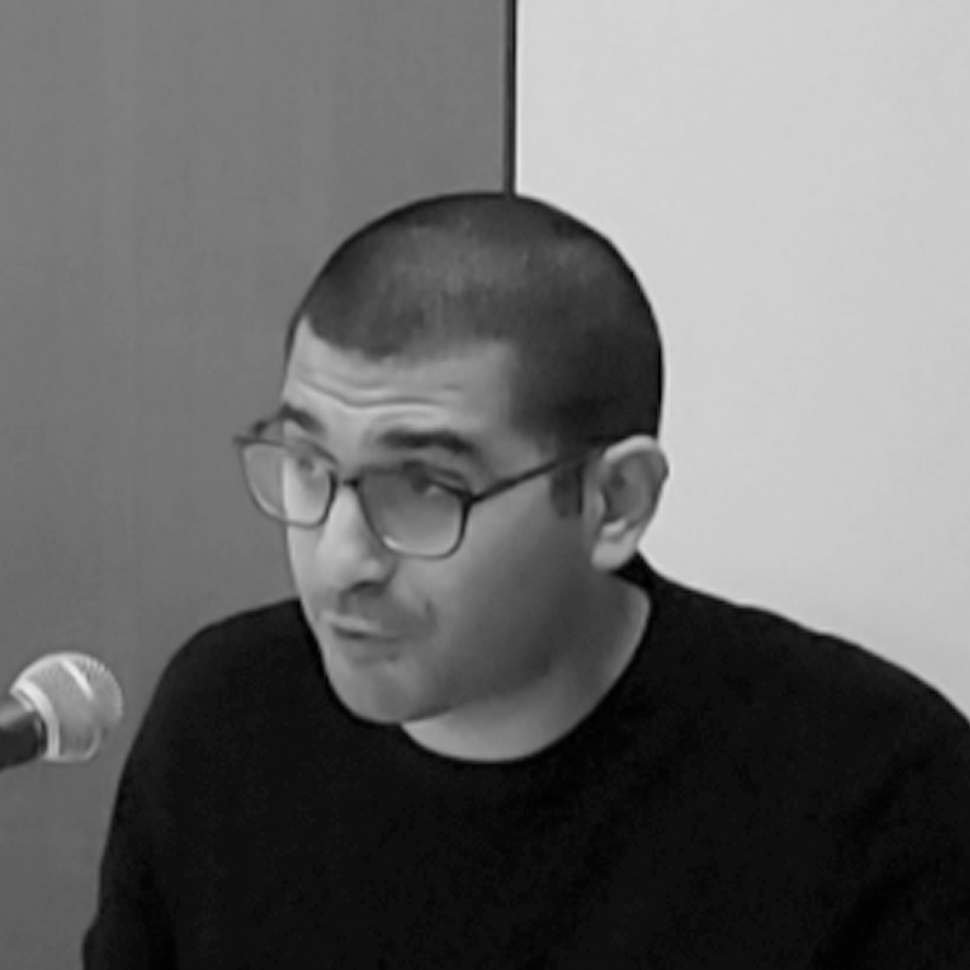 a man with glasses sitting in front of a microphone