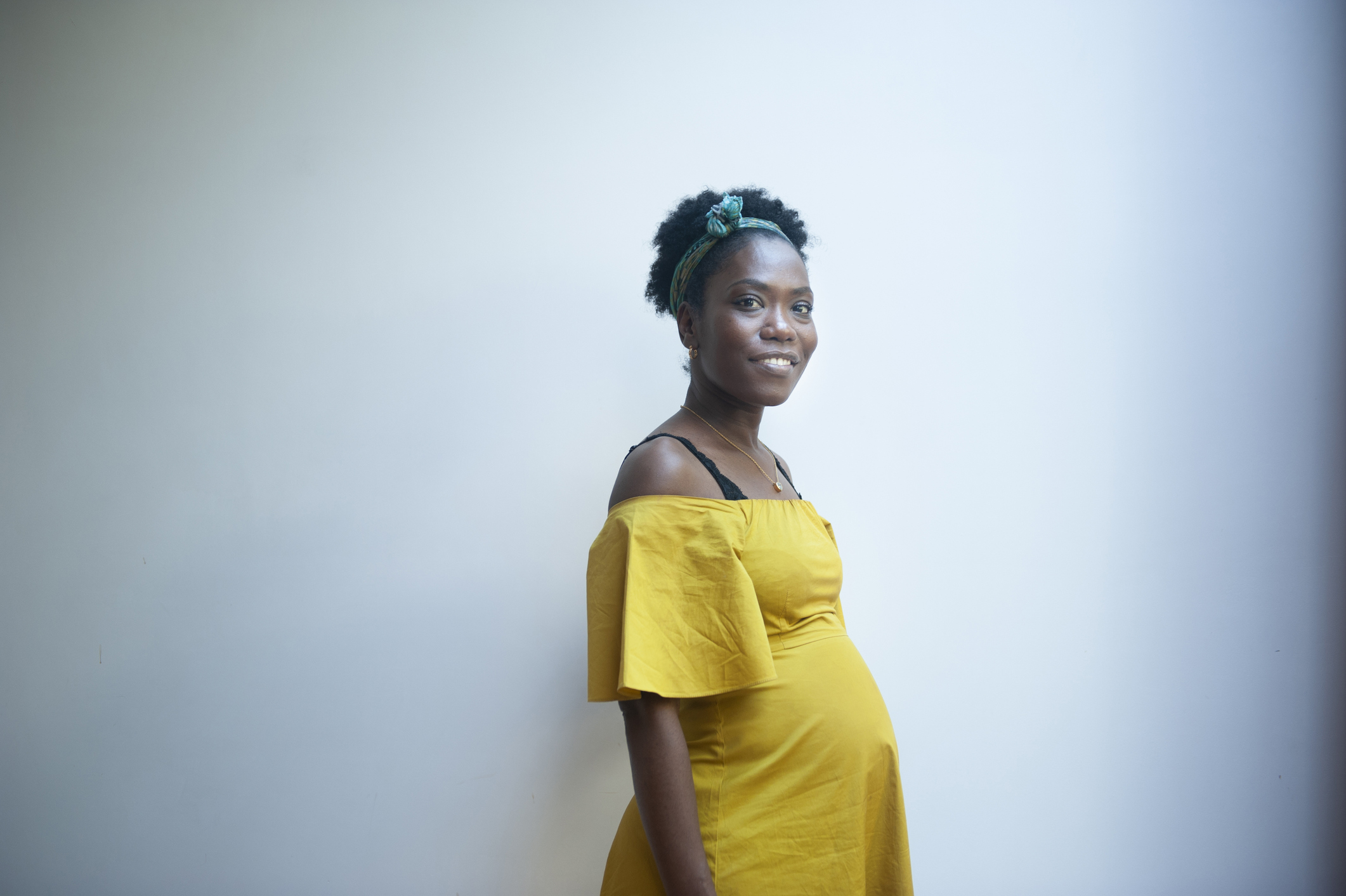 Indoors portrait of a beautiful pregnant woman, dressed in yellow.