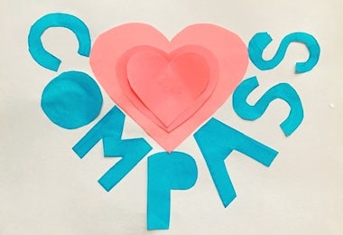 Children's artwork with a pink heart and the word Compass cut out of construction paper.