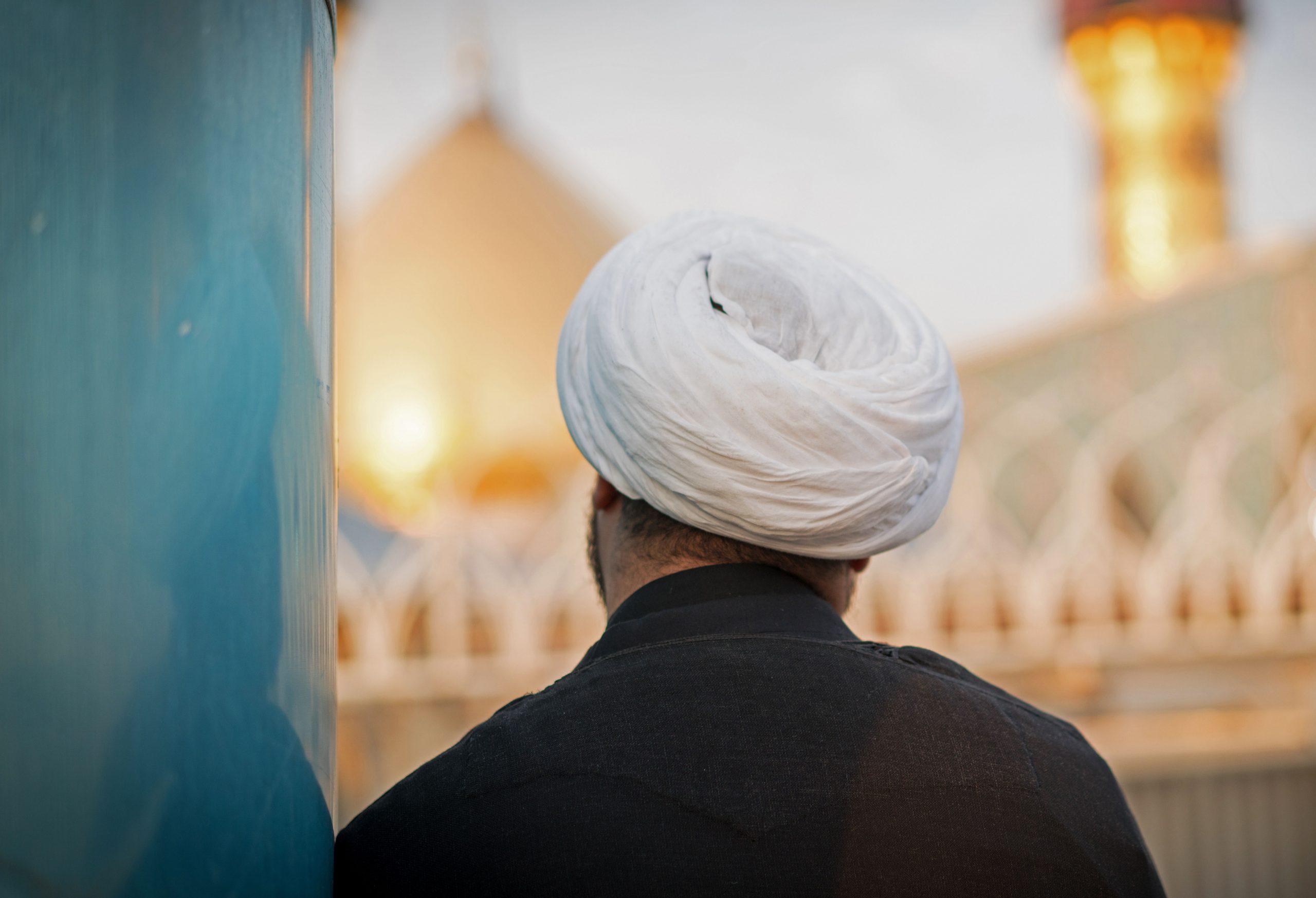 Muslim religious man in Karbala with Shrine of Imam Hussein in background