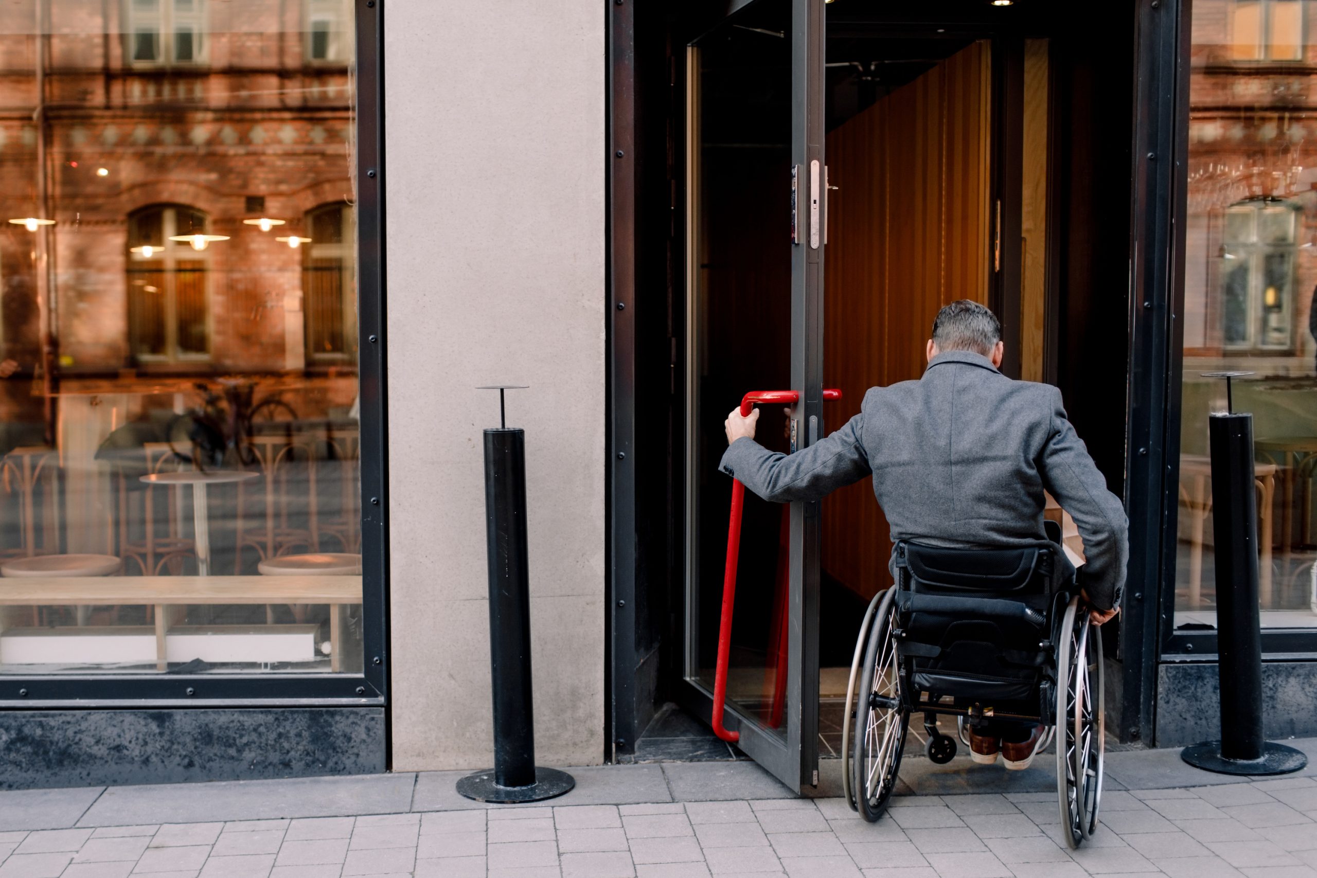 Rear view of disabled mature man sitting on wheelchair while entering in store.