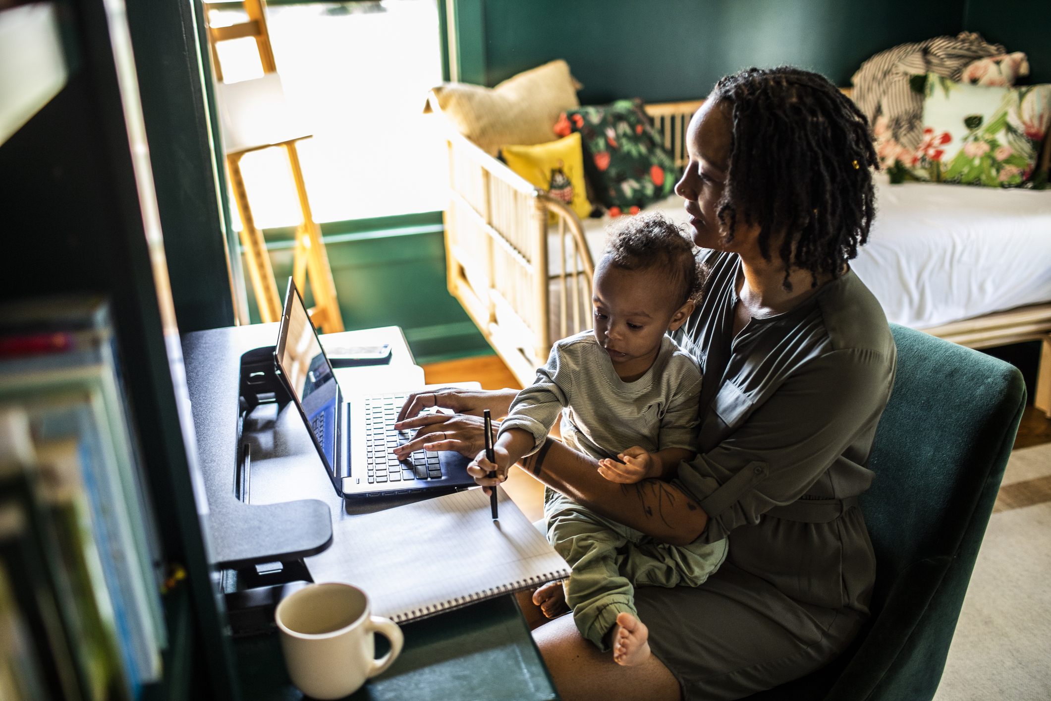 Woman working from home while holding toddler