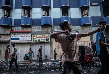 BAGHDAD, IRAQ - NOVEMBER 15: A young Iraqi protestor lauches rocks with a slingshot at Iraqi security forces near Al-Senak bridge on Nov. 15, 2019 in Baghdad, Iraq. Al-Senak bridge has been a contested area where protestors have continued to advance their movements pushing northwest as Iraqi security forces aim to maintain their position. Since Oct. 1, thousands of demonstrators have occupied various parts of Baghdad including its main bridges and Tahrir Square calling for government and policy reform. For many, Tahrir Square, which protesters are calling