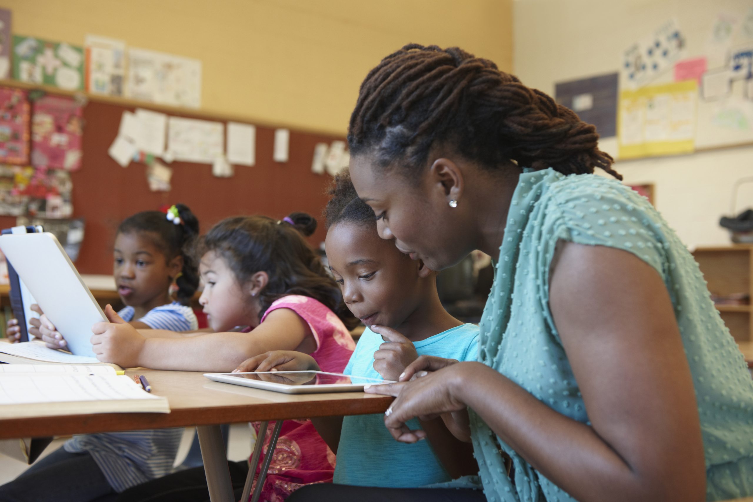 Teacher helping student with digital tablet
