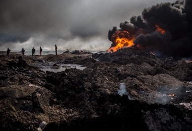 QAYYARAH, IRAQ - DECEMBER 23: Fire crews work to extinguish a burning oil well on the outskirts of Qayyarah on December 23, 2016 in Qayyarah, Iraq. The fire crews, brought in from Kirkuk, have been working tirelessly with oil company representatives to extinguish the oil wells set ablaze by Daesh on their retreat from the city more than two months ago. The fire crews are currently working on their ninth oil well after extinguishing nearly all the wells close to the city. (Photo by Chris McGrath/Getty Images)