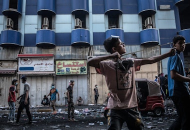 BAGHDAD, IRAQ - NOVEMBER 15: A young Iraqi protestor lauches rocks with a slingshot at Iraqi security forces near Al-Senak bridge on Nov. 15, 2019 in Baghdad, Iraq. Al-Senak bridge has been a contested area where protestors have continued to advance their movements pushing northwest as Iraqi security forces aim to maintain their position. Since Oct. 1, thousands of demonstrators have occupied various parts of Baghdad including its main bridges and Tahrir Square calling for government and policy reform. For many, Tahrir Square, which protesters are calling