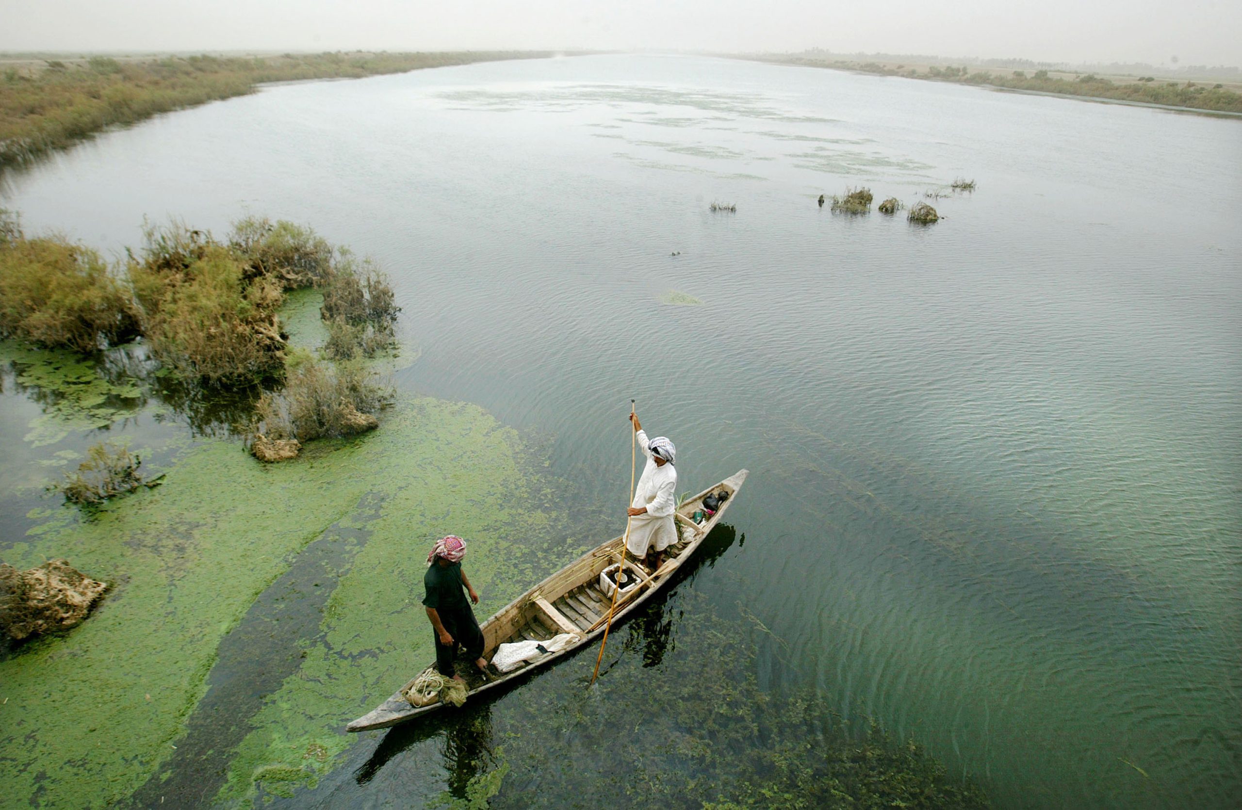 AL-FOHUD, IRAQ - JUNE 3:  A Marsh Arab guides his boat through a marsh area that is slowly being re-flooded with water June 3, 2003 in Al-Fohud, Iraq. The Marsh Arabs have inhabited the swamplands in the area for approximately 5,000 years, but their lifestyle was virtually destroyed by Saddam Hussein following the 1991 Shiite uprising in the region. Hussein constructed dams and diverted waterways to drain the marshes in an effort to destroy the Marsh Arabs. Following the war, some dams have been re-opened allowing the marshes to slowly begin to refill and some Marsh Arabs are beginning to return to their old lifestyle.  (Photo by Mario Tama/Getty Images)