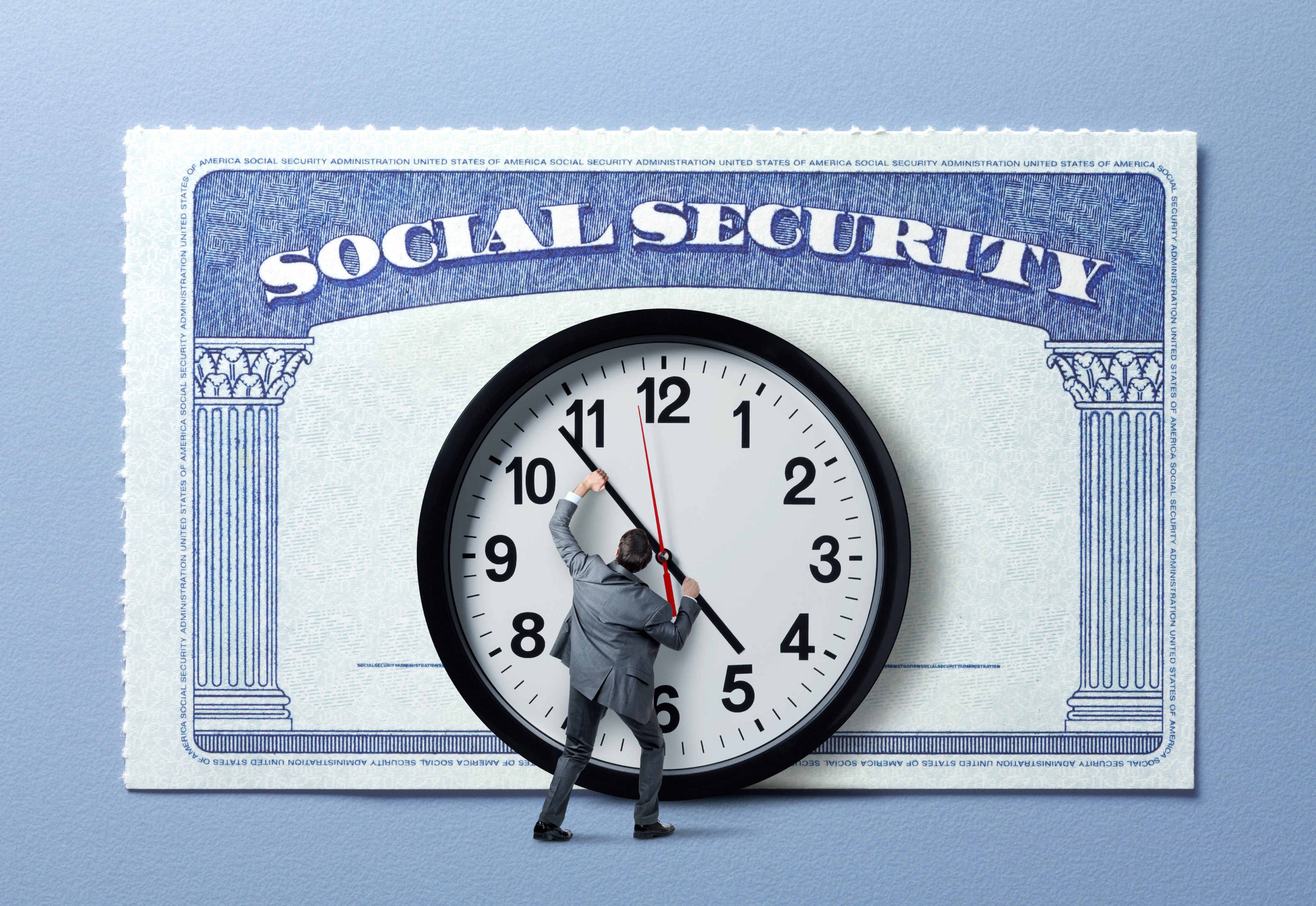A man trying to stop the hands of a large clock that is attached to an even larger social security card.
