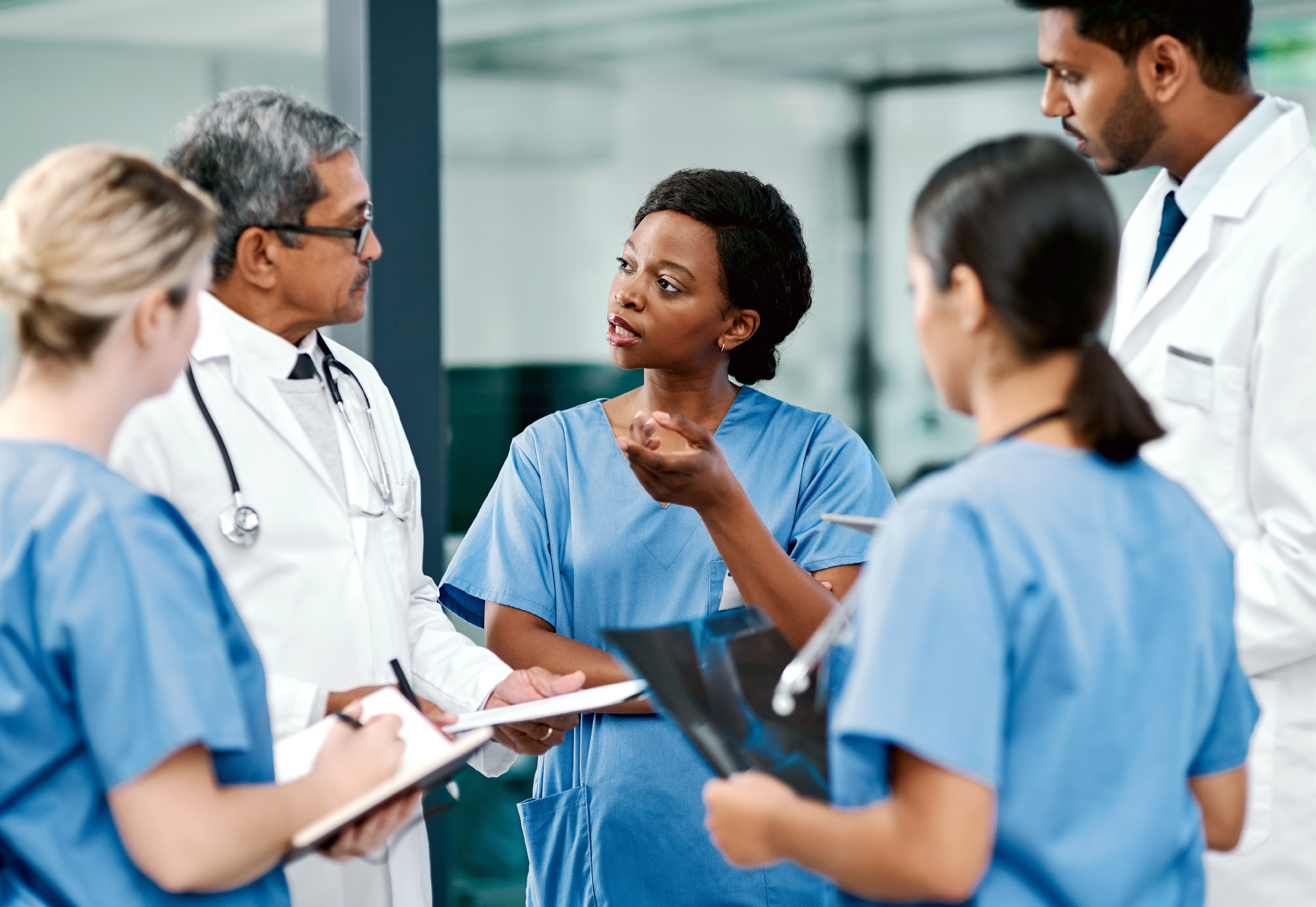 A Black medical professional is standing in a group, talking to her colleagues.