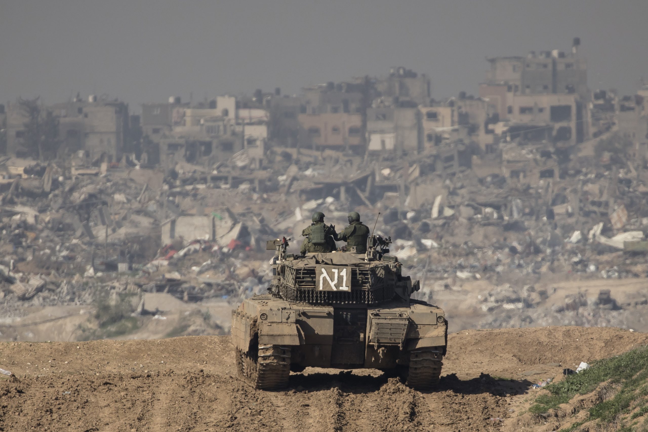SOUTHERN ISRAEL, ISRAEL - JANUARY 19: Israeli soldiers stand on a tank as they secure the border with the Gaza Strip, as seen from a postion on the Israeli side of the border on January 19, 2024 in Southern Israel, Israel. Israel increased air raids in the south of the Gaza Strip, where medicines are expected for hostages held by Hamas and humanitarian aid for the Palestinian population. Despite Israel's recent troop drawdown in Gaza and the discussion of postwar plans by an Israeli cabinet minister, the country has continued its intensive bombardment of the Gaza Strip, particularly in the territory's south, as it seeks to destroy Hamas, the Palestinian militant group behind the Oct. 7 attacks. At least 1,200 civilians and soldiers have been killed in Israel since October 7 along with some 190 IDF soldiers killed fighting in Gaza ground operations, while more than 24,000 people have been killed in Gaza in the last three months, according to the territory's health ministry, and most of the population has been displaced. (Photo by Amir Levy/Getty Images)