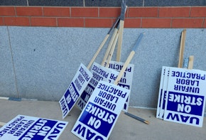 Labor union on strike picketing signs resting on a wall.