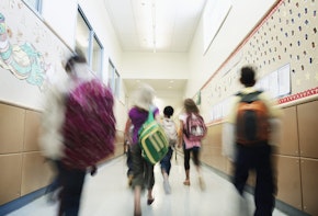 Young students with backpacks walking down hallway of elementary school