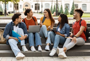 College Lifestyle. Group Of Students Relaxing Together Outdoors, Sitting On Stairs In Campus Park, Cheerful Millennial Men And Women Chatting And Laughing, Multiethnic Friends Resting After Classes