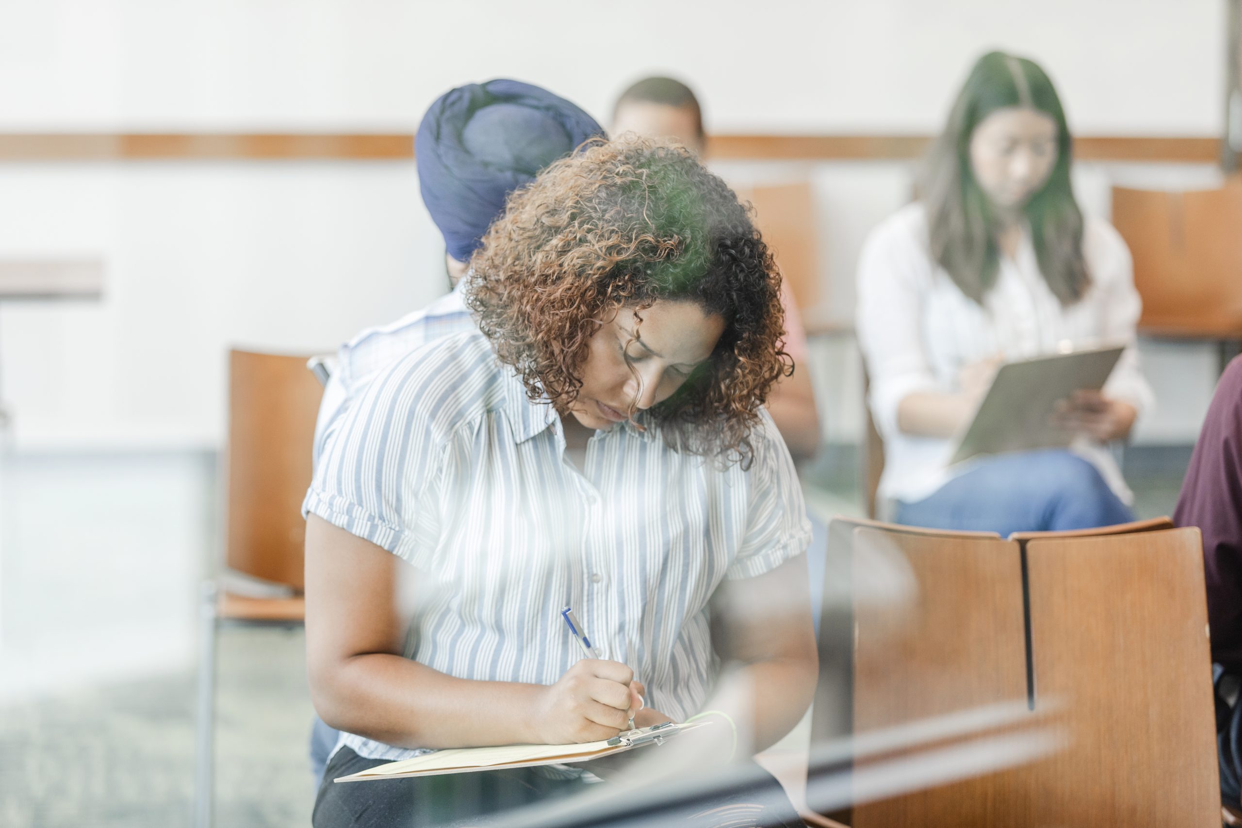 While waiting to see the doctor, the mid adult woman carefully fills out her paperwork.