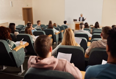 Back view of large group of students paying attention on a class at lecture hall.