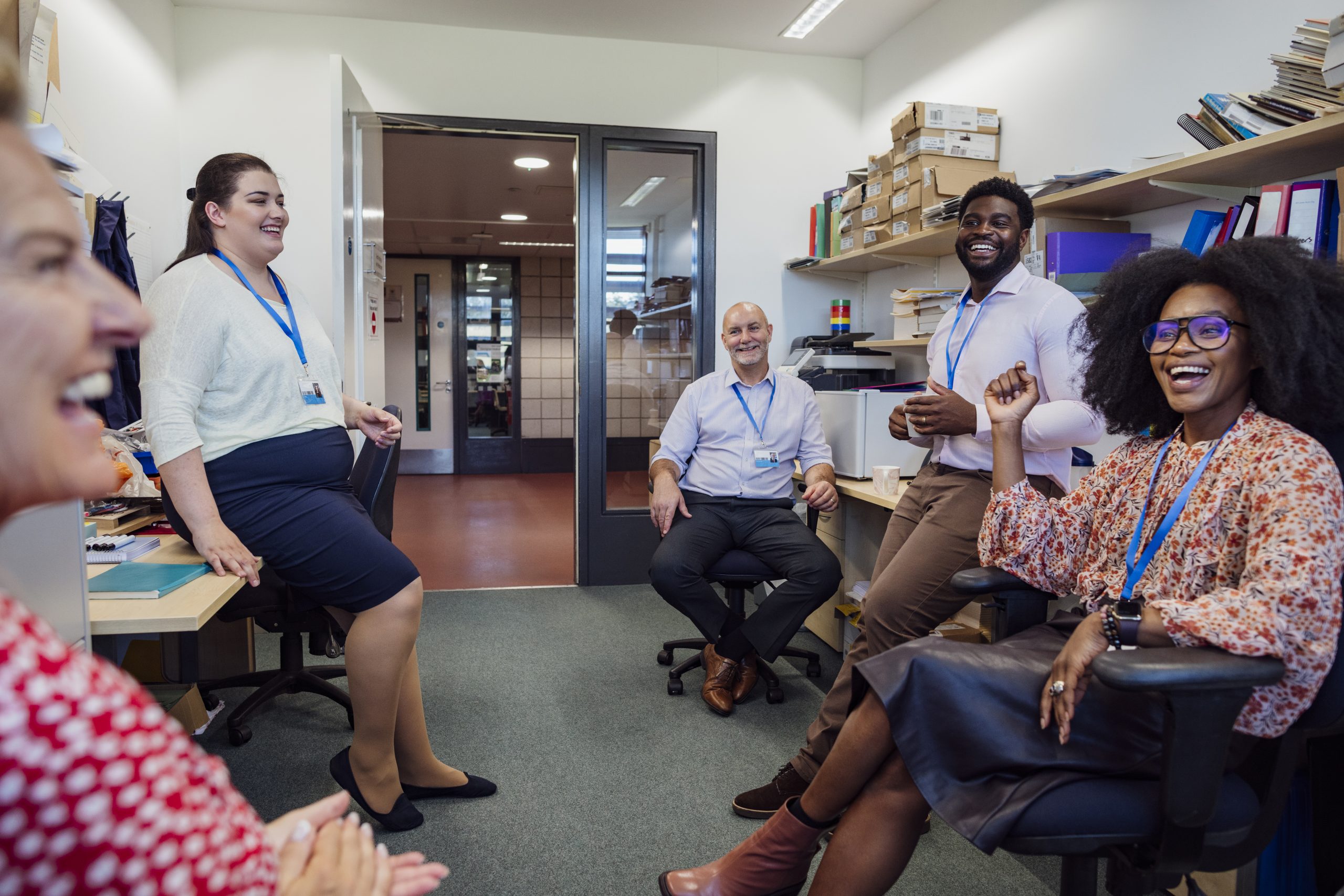 Teachers in an office together in the school that they work at in Gateshead, North East England. They are taking a break from teaching and laughing with each other.