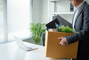Young businessmen wear gray suits, feel stressed and are packing items into cardboard boxes. Unemployment and business concepts