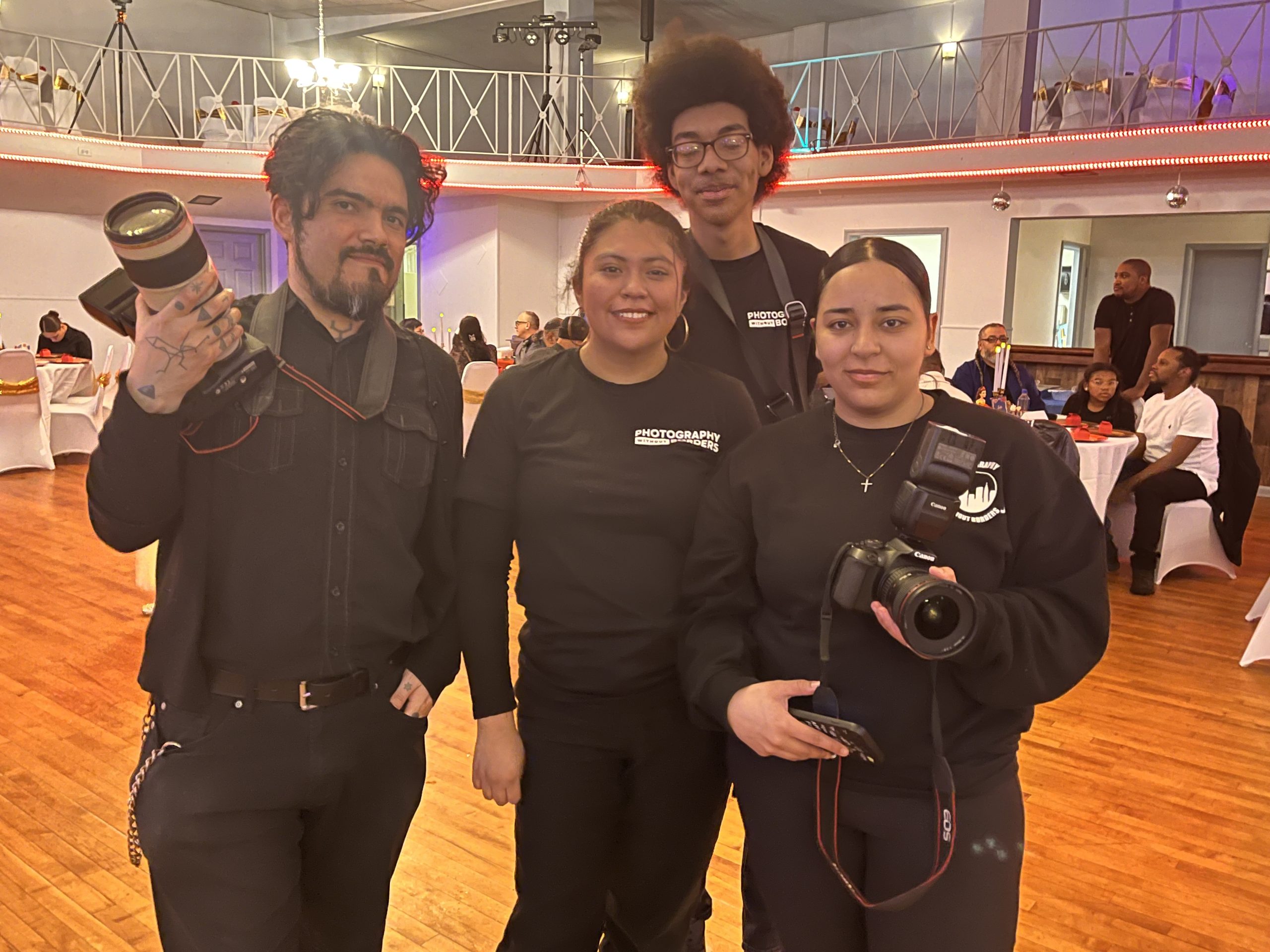 Four members of the Photography Without Borders afterschool program pose with their cameras