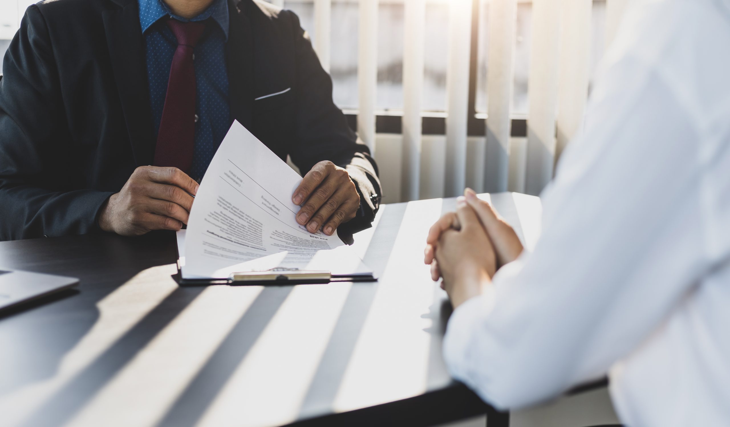 Employer in suit reading resume of job interview candidate profile collection. Woman explaining her profile to a business manager sitting for a job interview. Job Search and Human Resources
