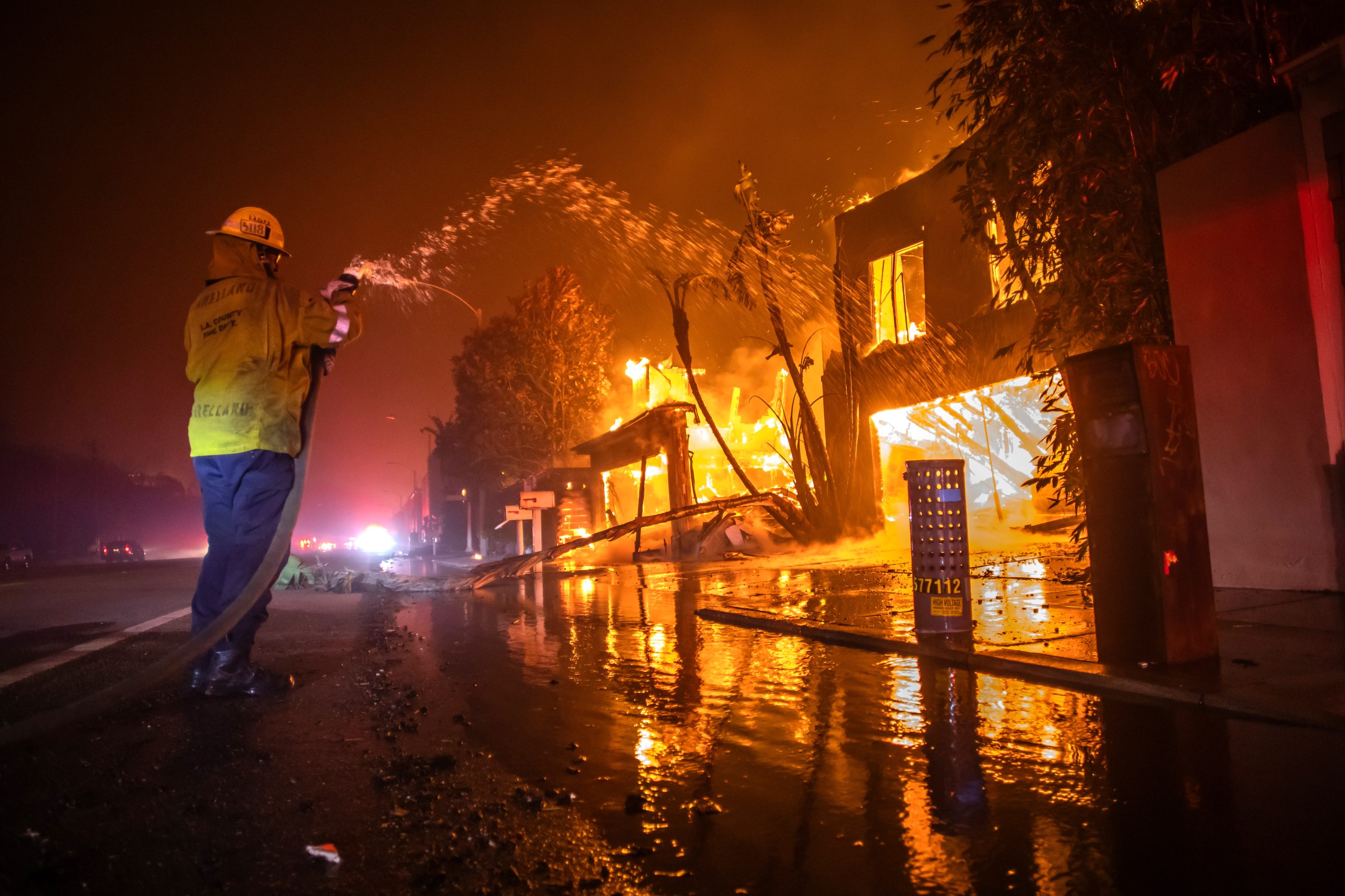 LOS ANGELES, CALIFORNIA - JANUARY 8: A firefighter battles the Palisades Fire while it burns homes at Pacific Coast Highway amid a powerful windstorm on January 8, 2025 in Los Angeles, California.  The fast-moving wildfire has grown to more than 2900-acres and is threatening homes in the coastal neighborhood amid intense Santa Ana Winds and dry conditions in Southern California. (Photo by Apu Gomes/Getty Images)