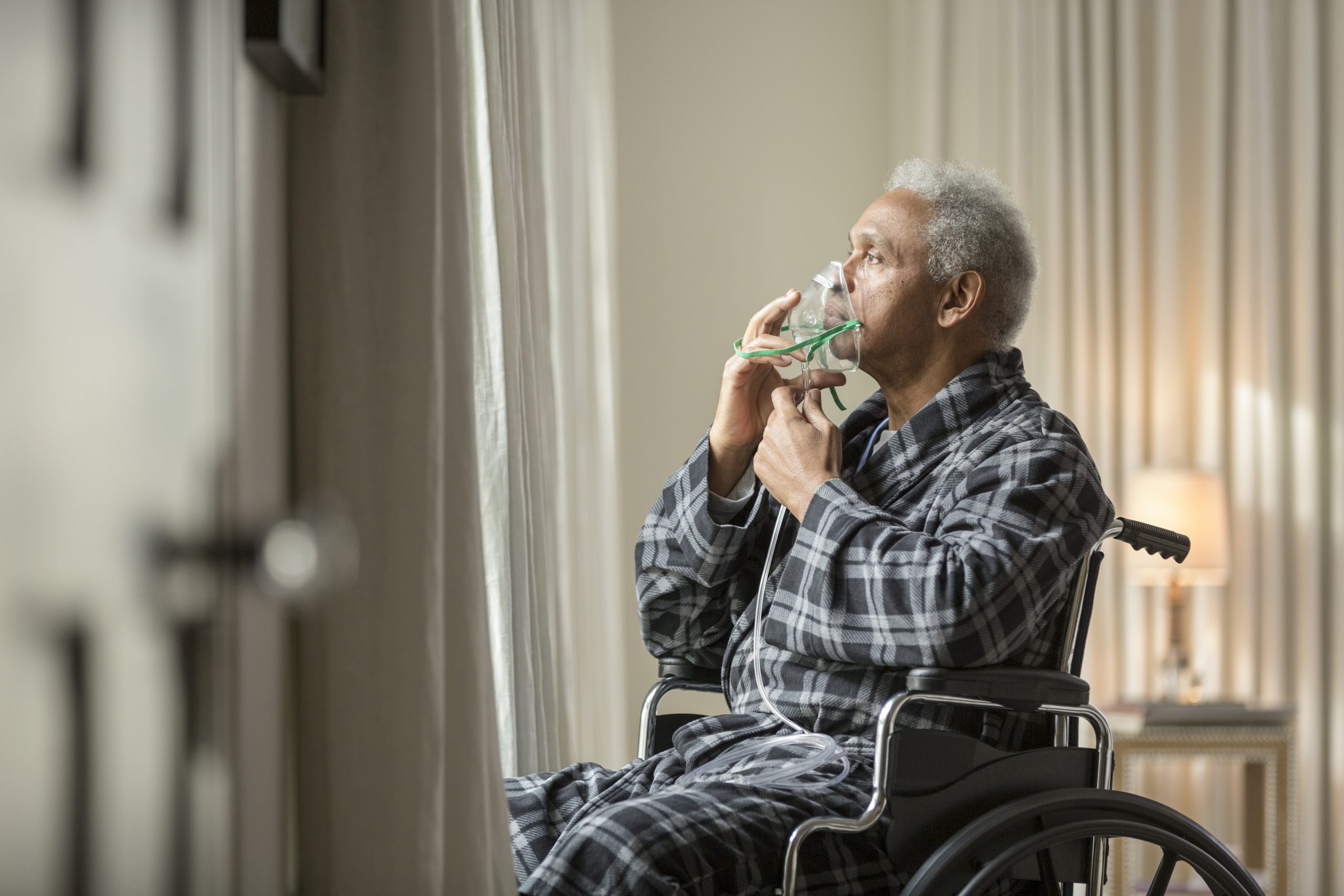 Senior African American man in wheelchair breathing with mask